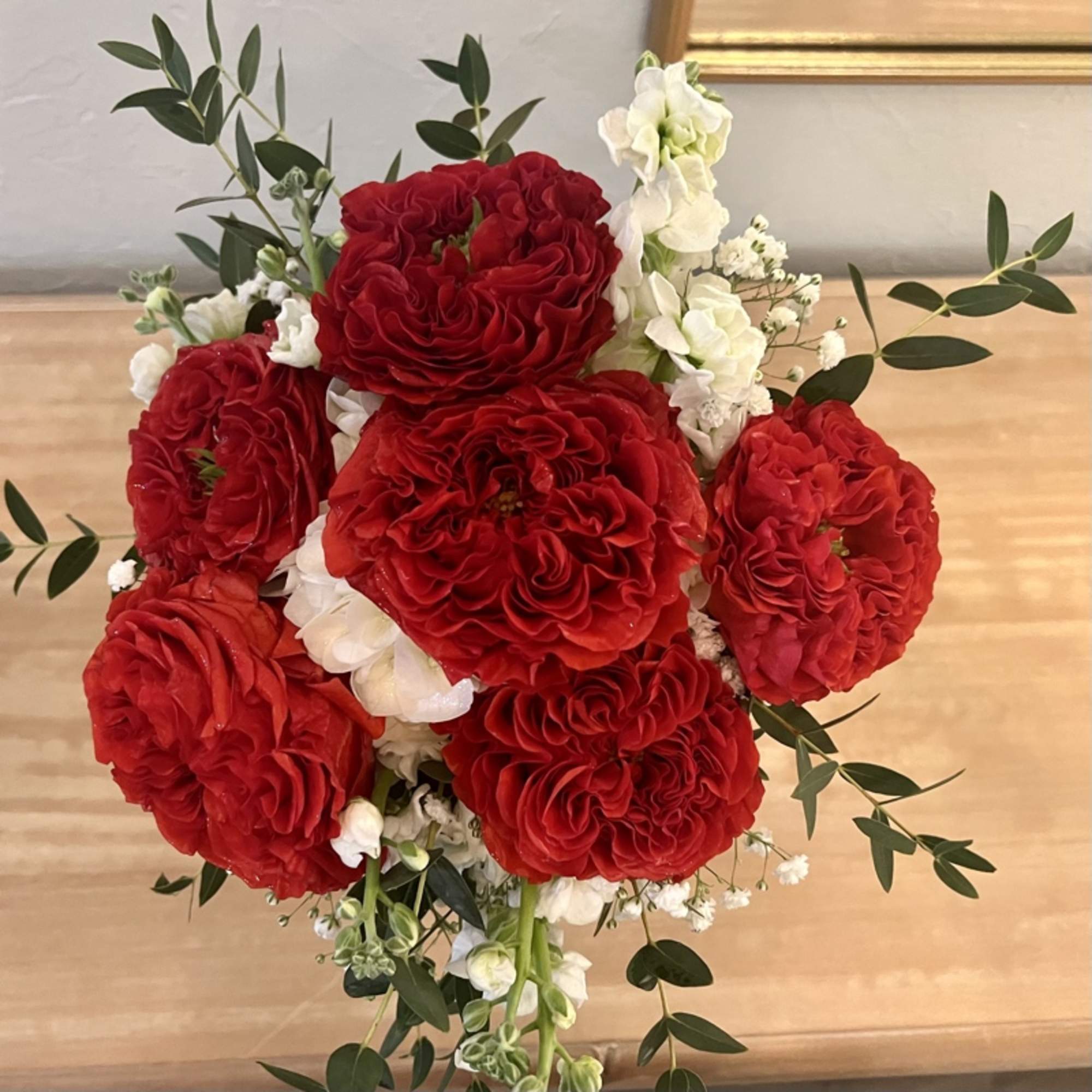 Hand-tied bouquet of ruffled red roses with white accent flowers.