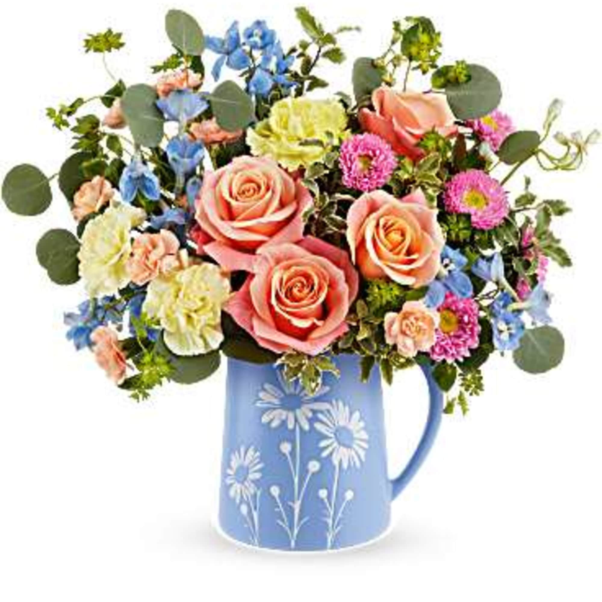 Mixed bouquet of peach roses, blue blooms, and pink flowers in a blue daisy-print pitcher