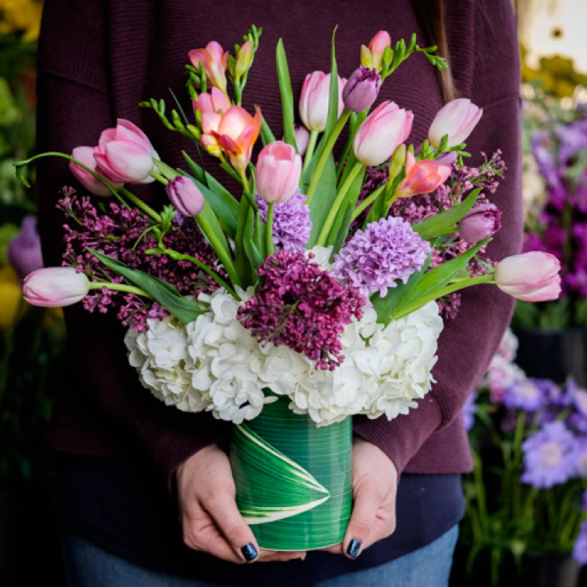Pink tulips and purple flowers arranged in a green vase