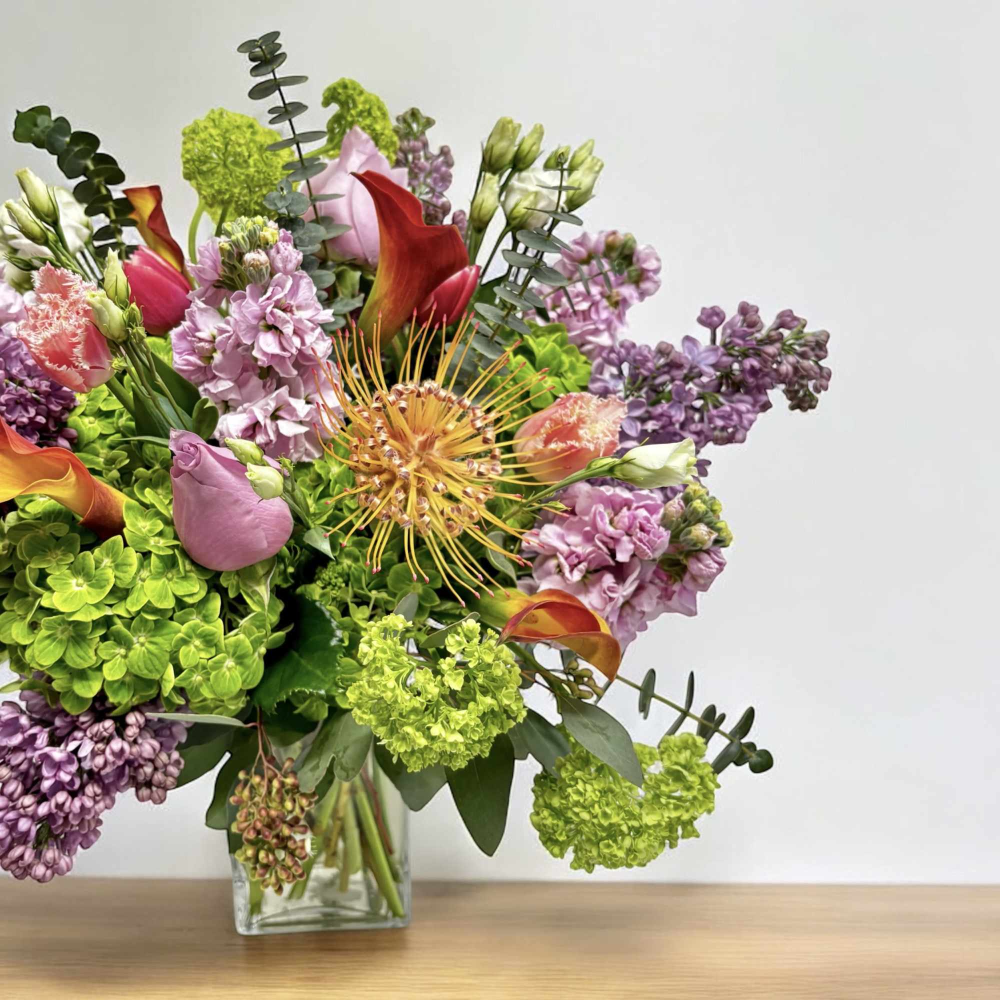 Mixed bouquet in a clear glass vase with pink, purple, and green blooms