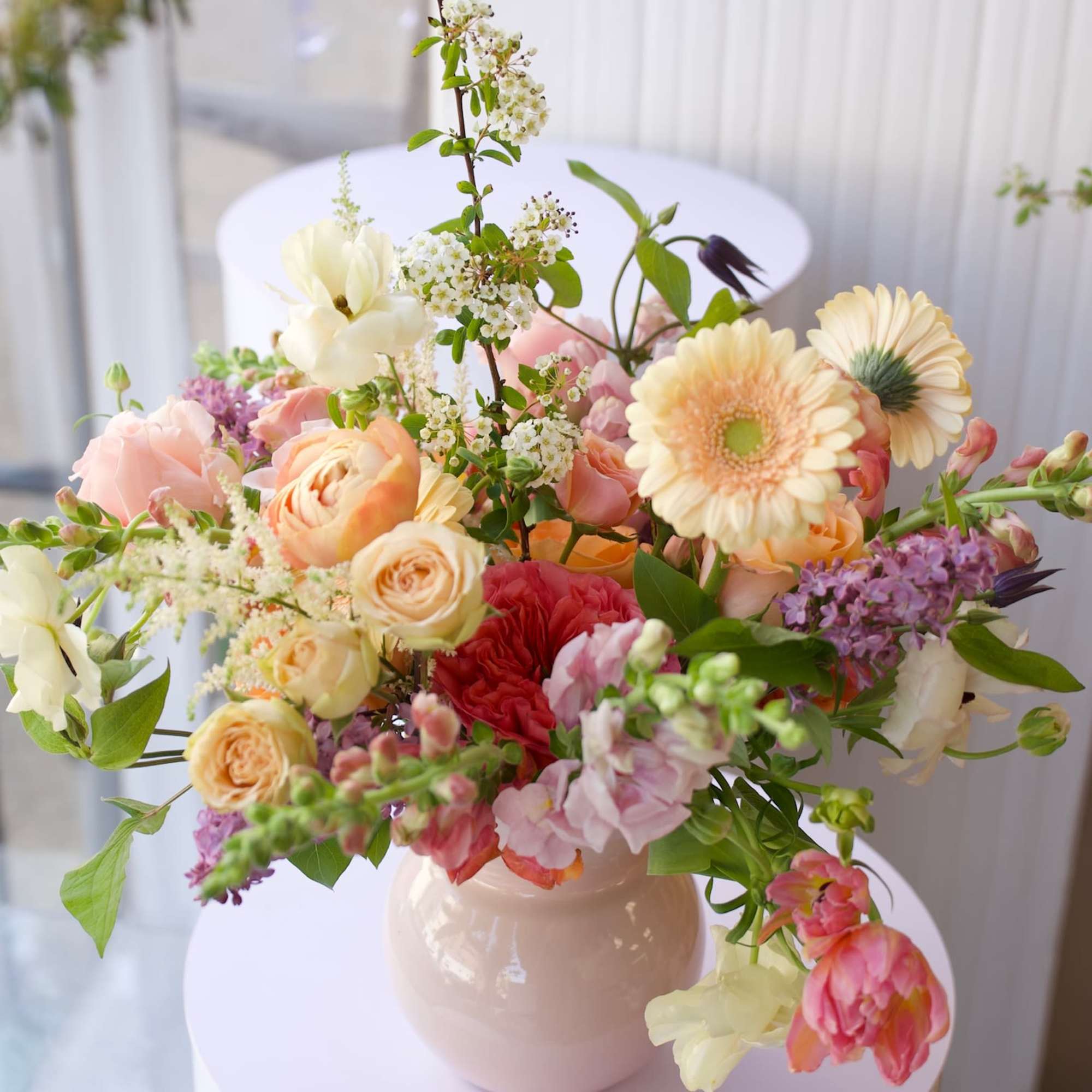 A soft, garden-style floral arrangement featuring apricot garden roses, ranunculus, tulips, snapdragons