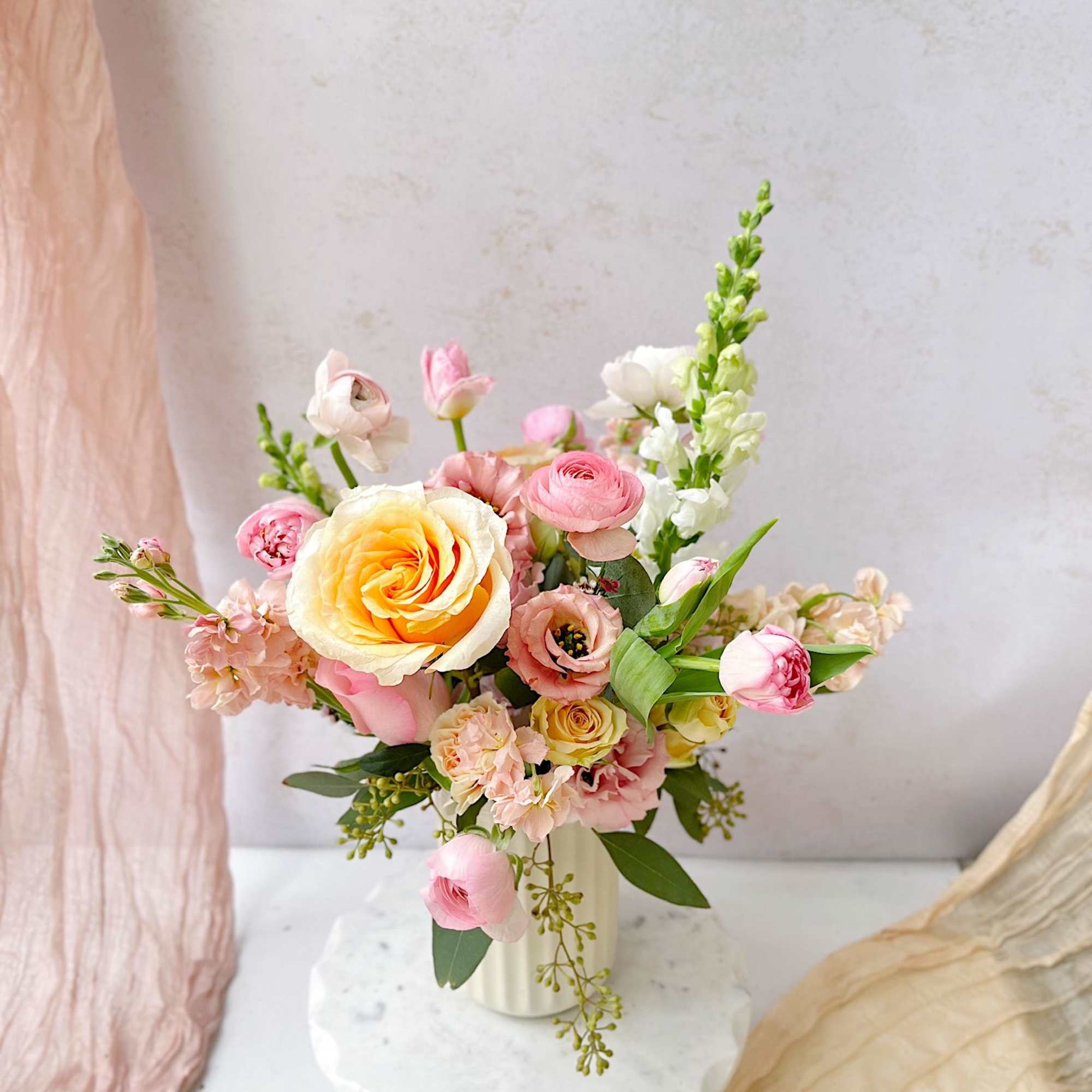 A soft and radiant spring vase arrangement featuring roses, ranunculus, tulips, lisianthus
