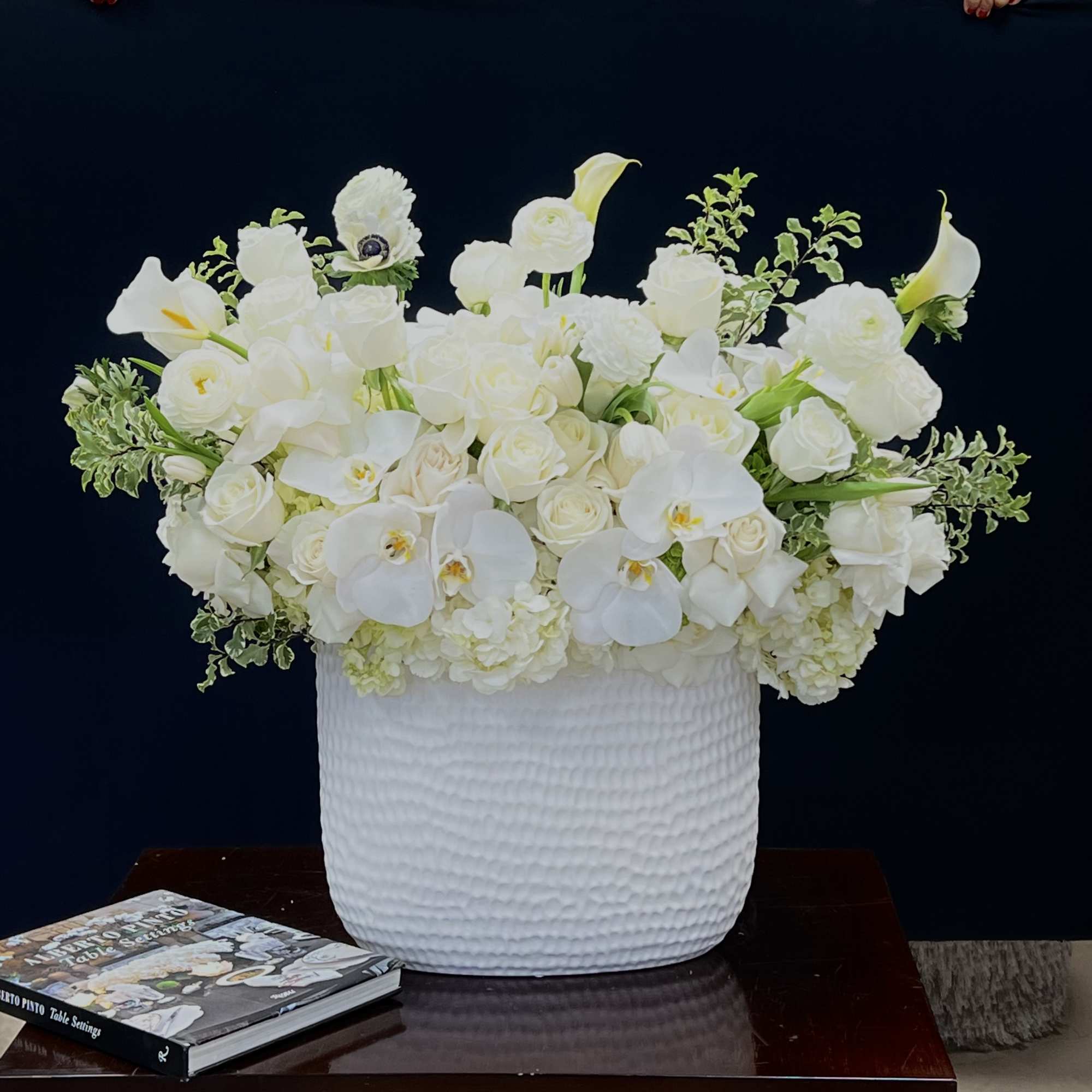 This tall vase arrangement features an array of white flowers including Phalaenopsis