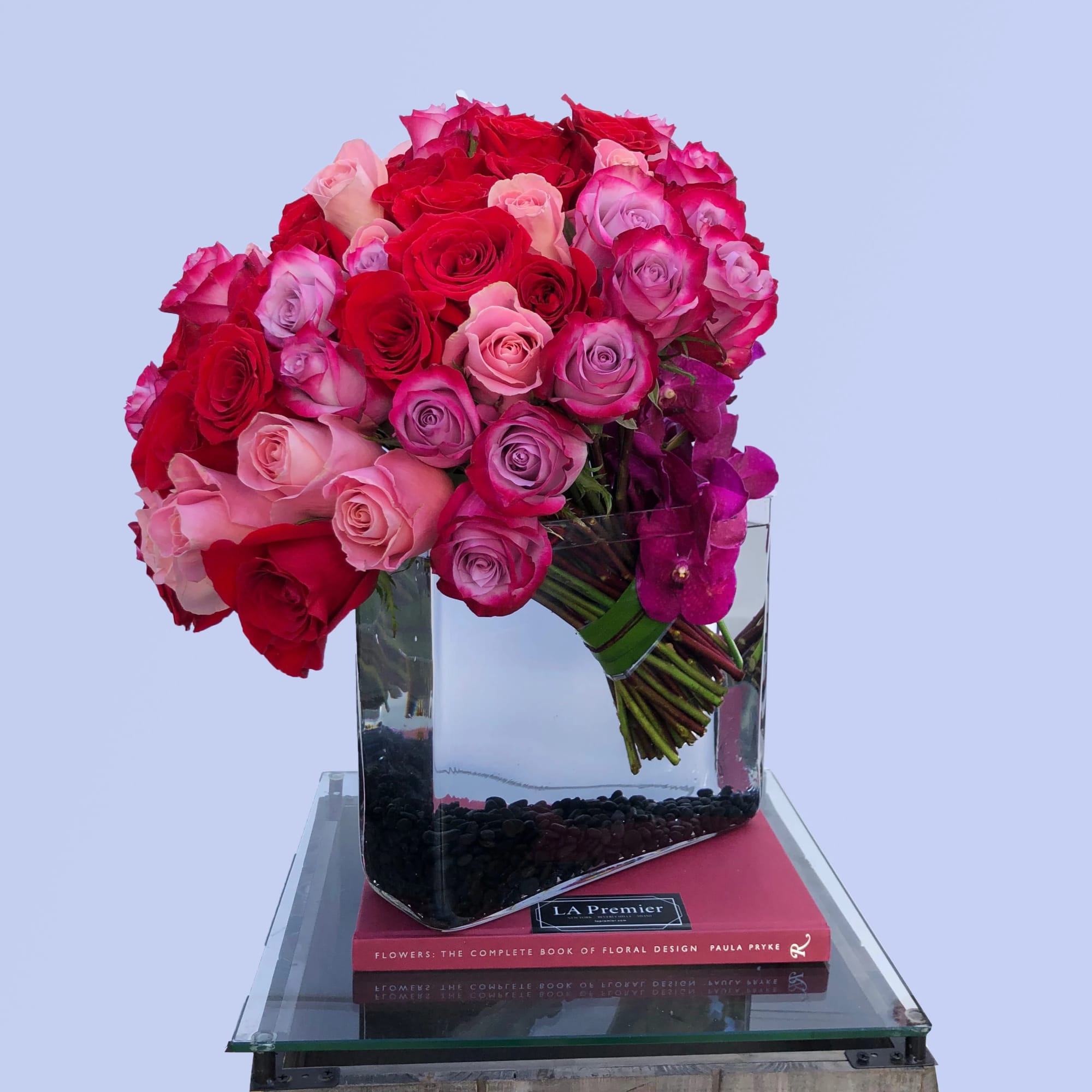Bouquet of red, pink, and purple roses in a clear glass vase