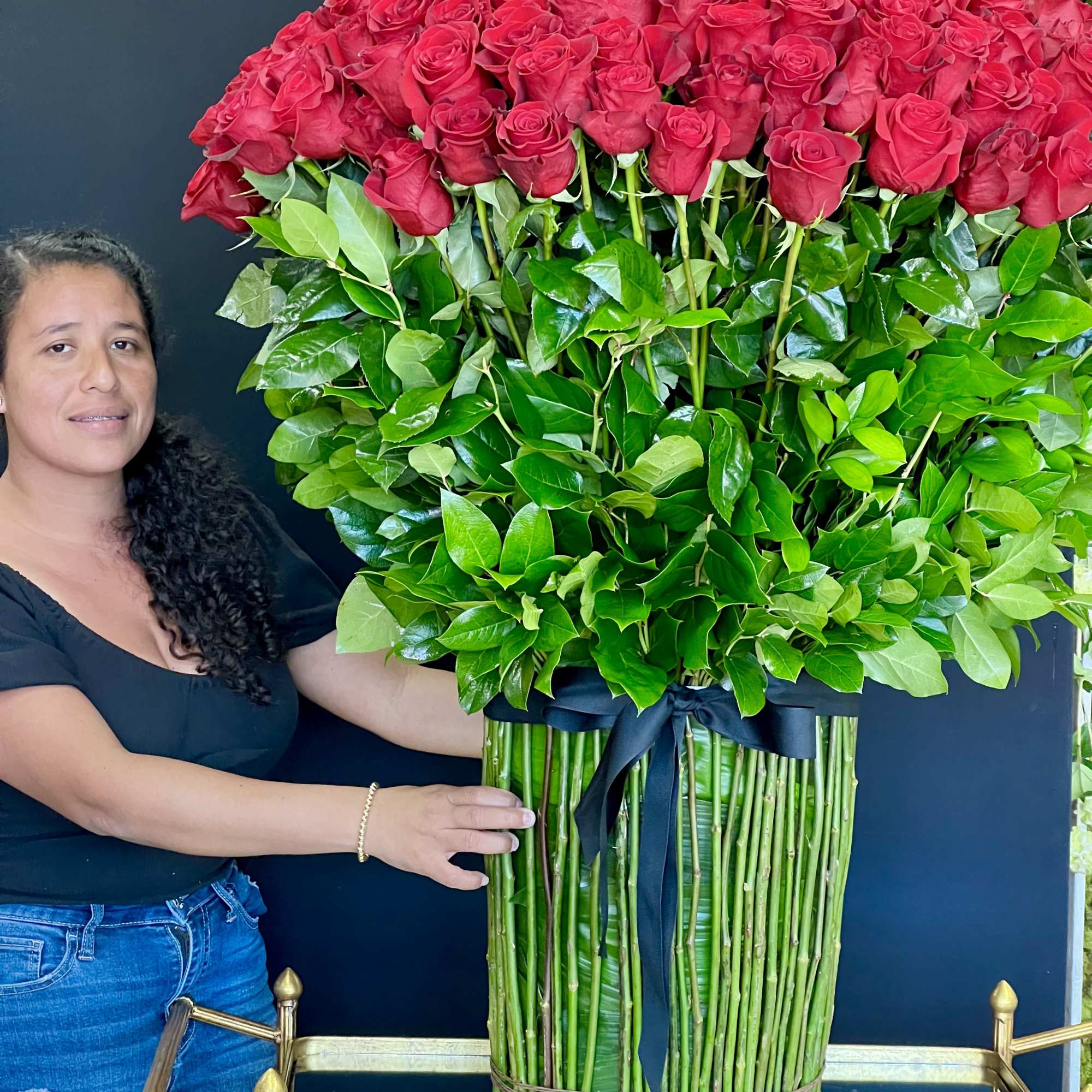 Large arrangement of red roses with lush greenery in a tall vase