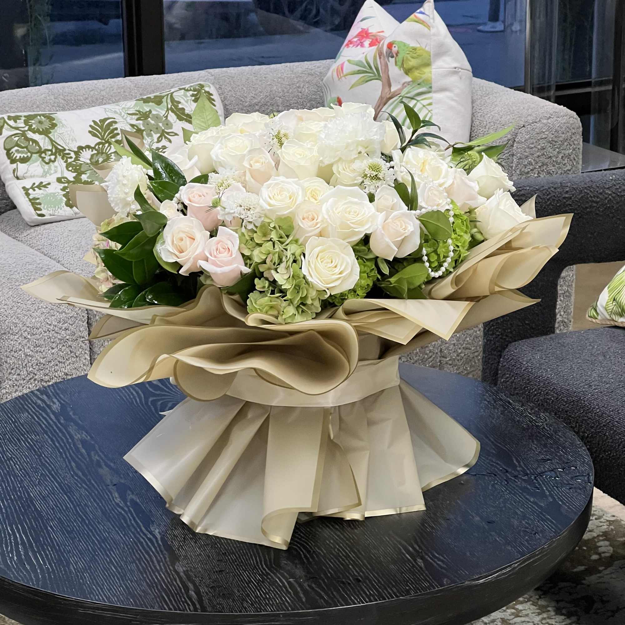 Bouquet of white and blush roses wrapped in beige paper