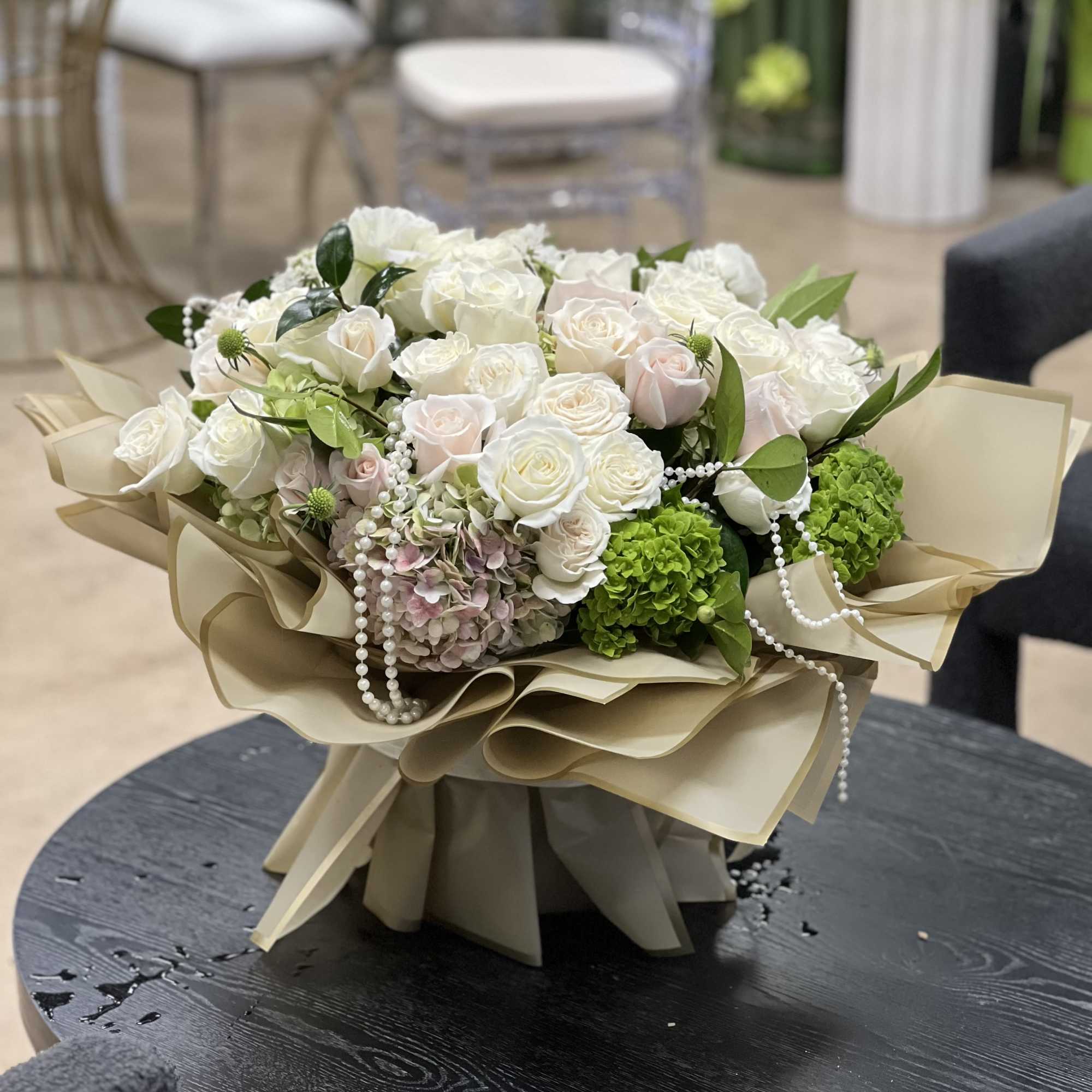 Bouquet of white roses and green hydrangeas wrapped in beige paper