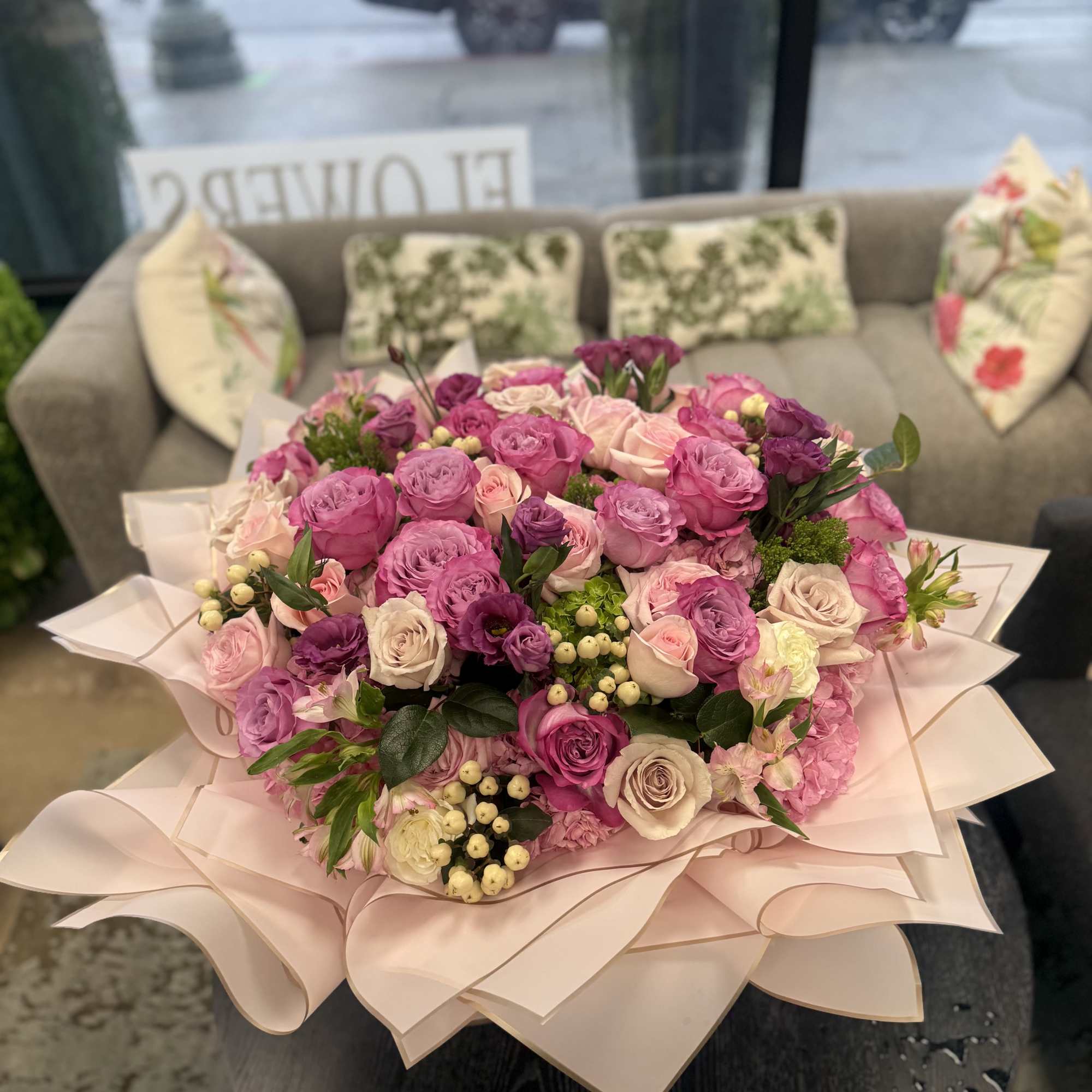 Large bouquet of pink and lavender roses wrapped in pale pink paper