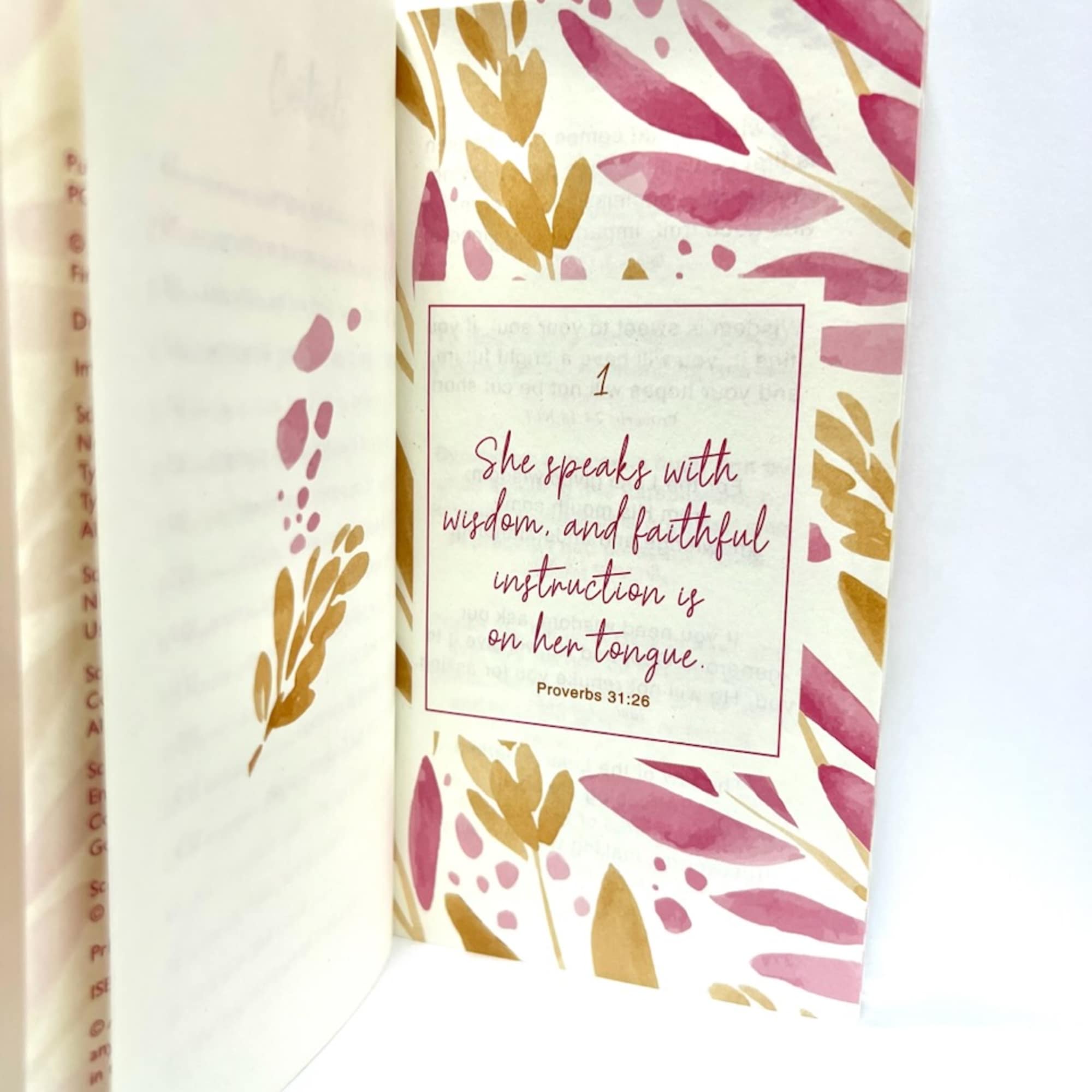 Open book page with pink and gold leaf pattern and a Bible verse