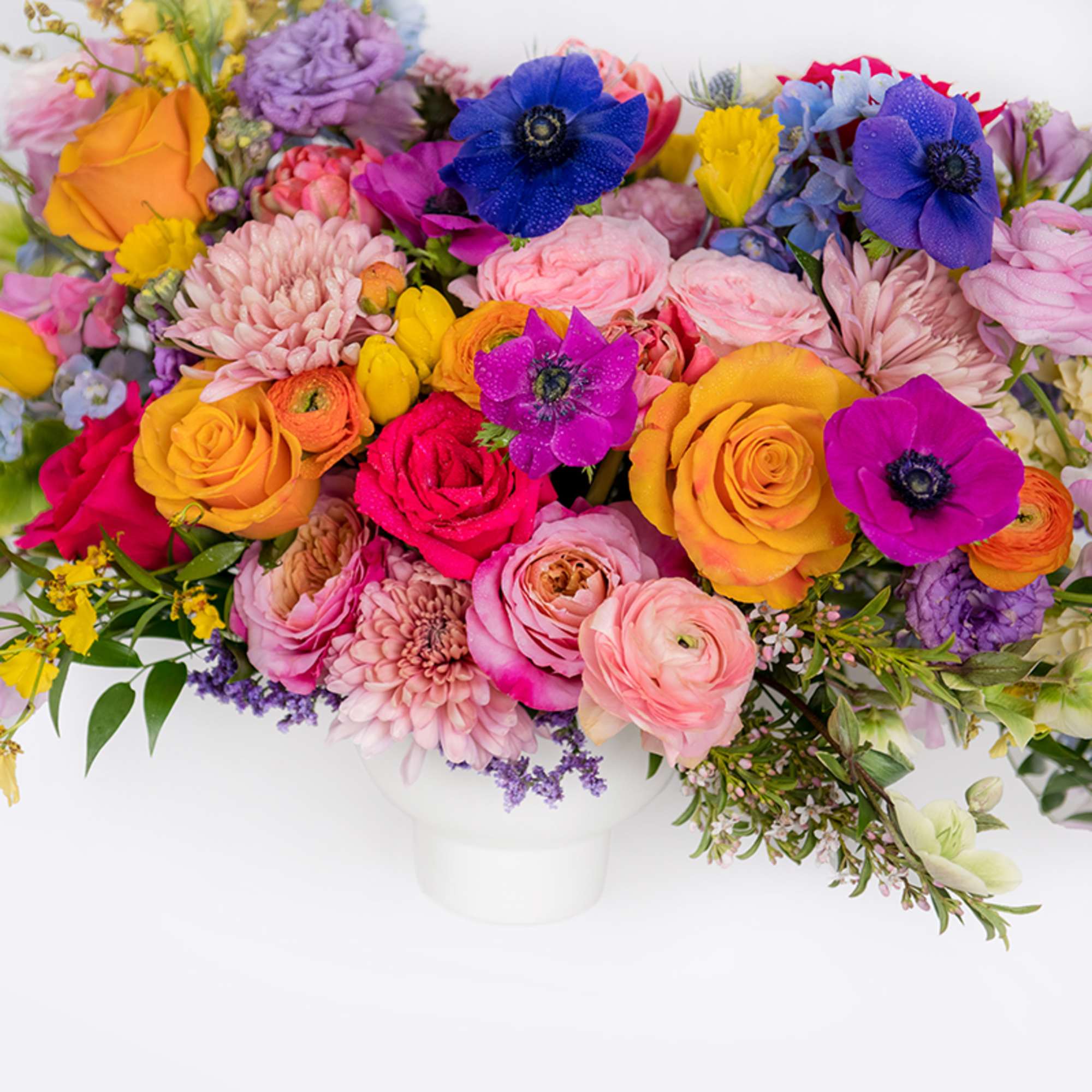 Low arrangement of bright pink, yellow, and purple flowers in a white ceramic bowl