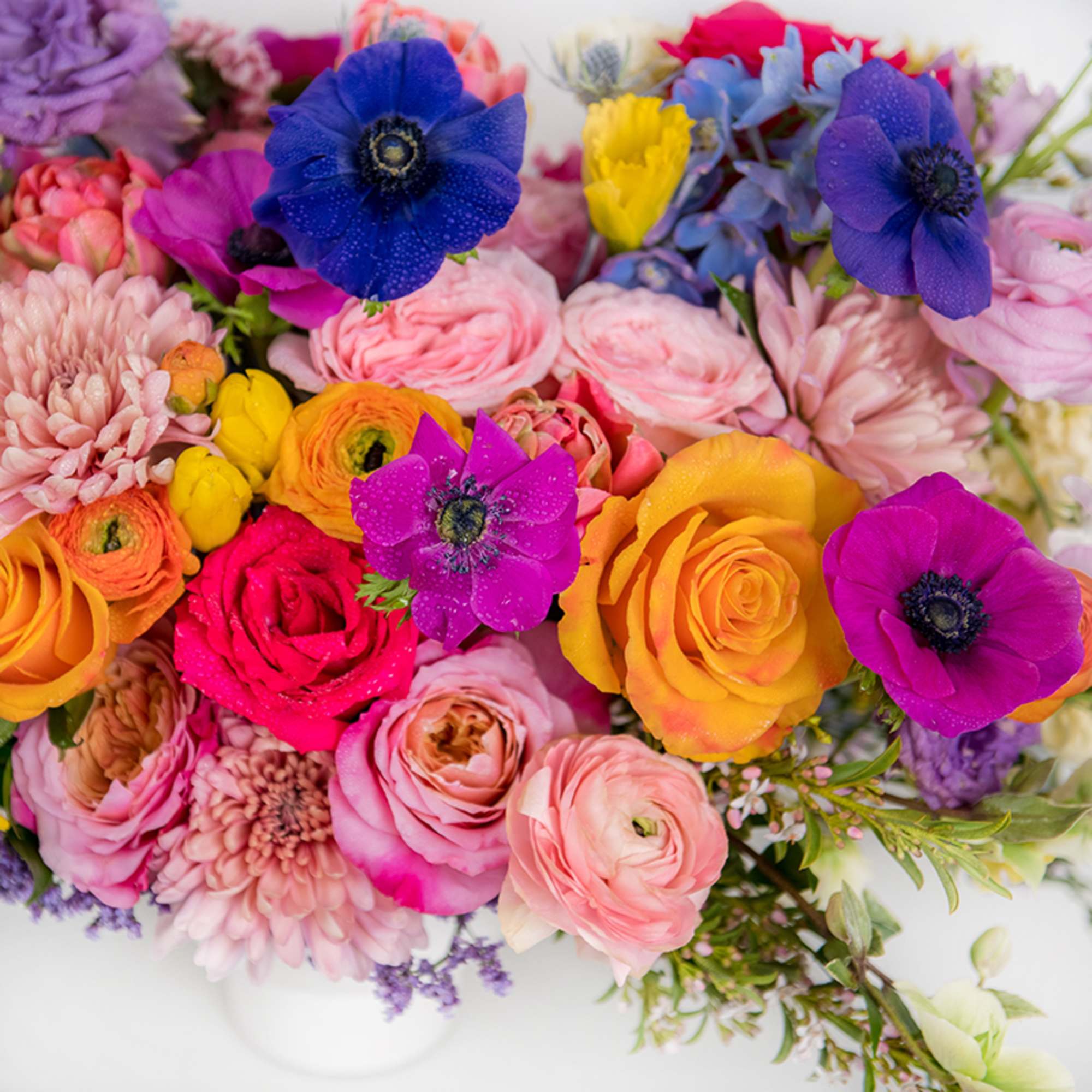 Bright mixed bouquet of pink roses and ranunculus with purple anemones and yellow blooms