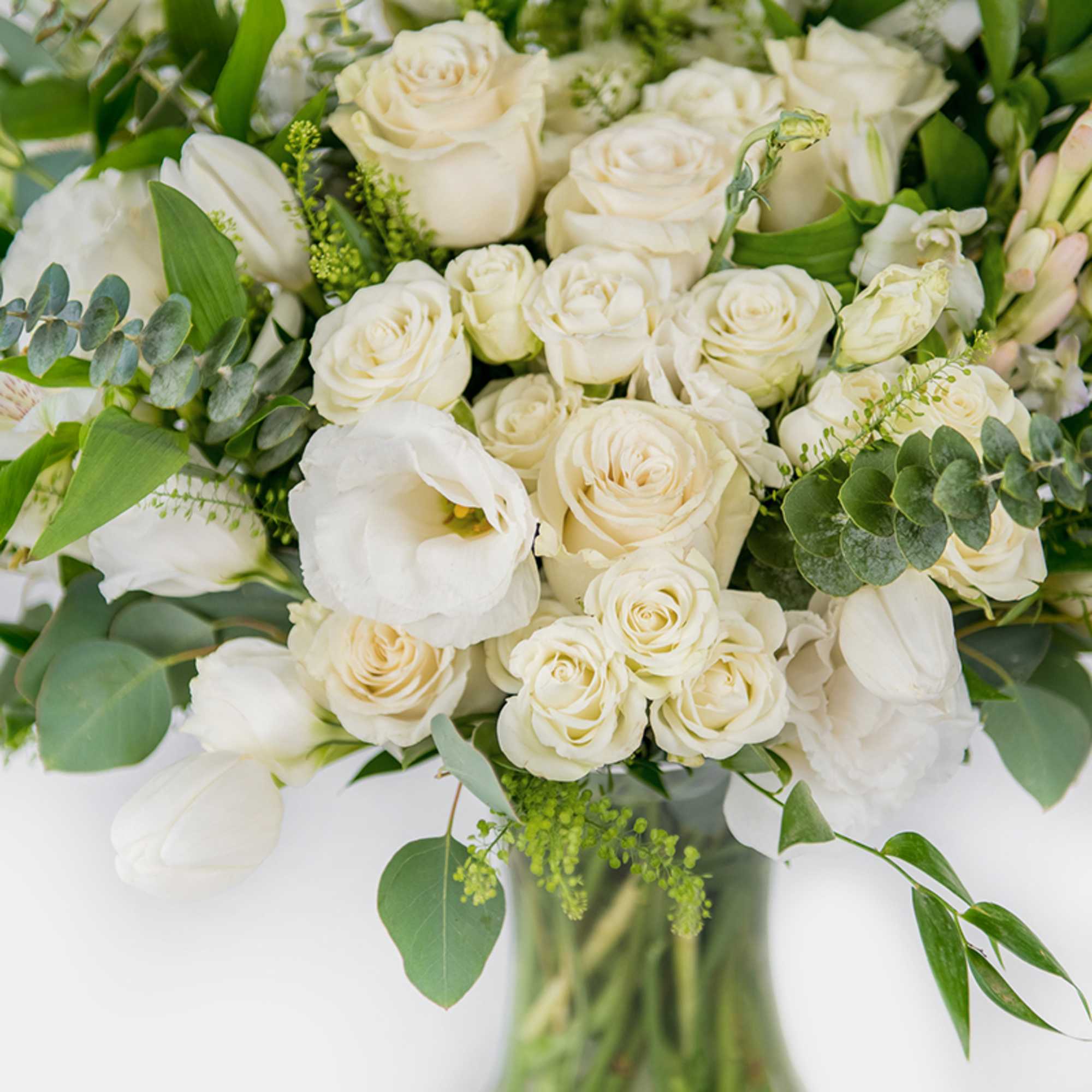 White roses and tulips arranged in a glass vase