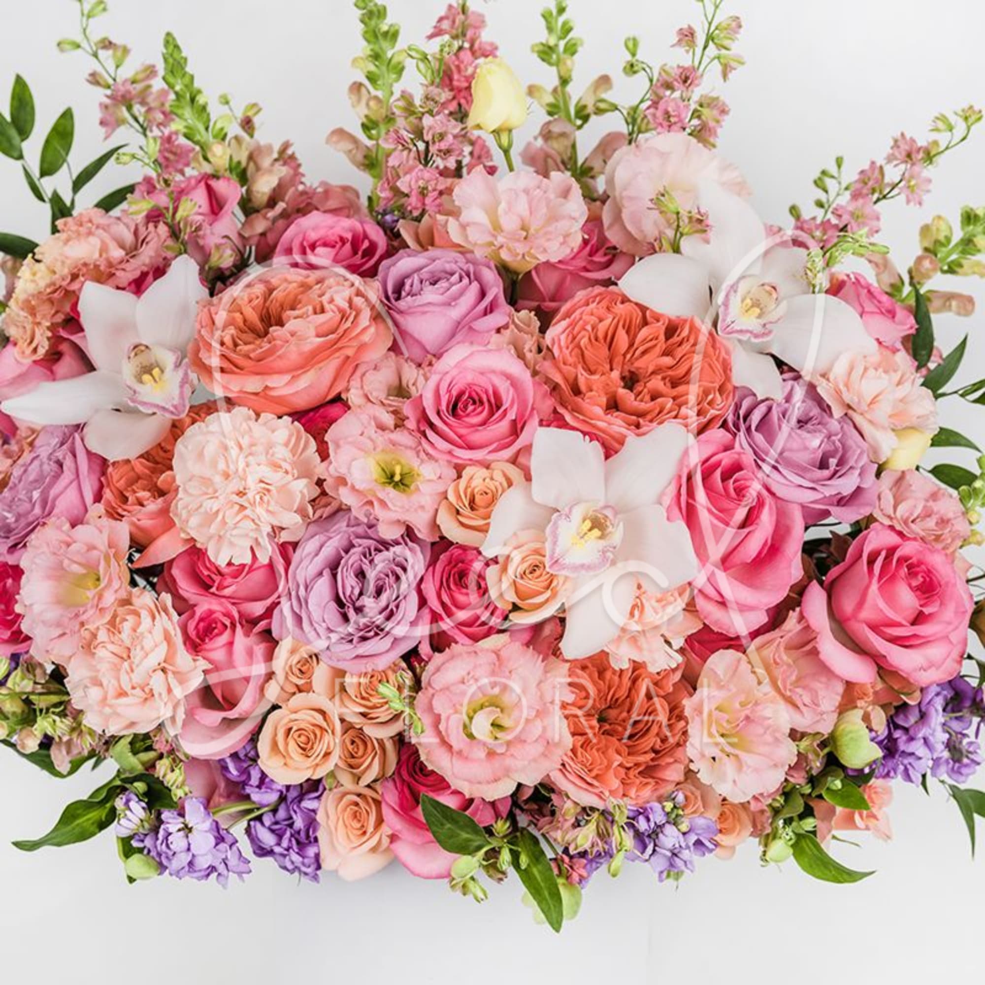 Large bouquet of pink, peach, and lavender flowers with white orchids