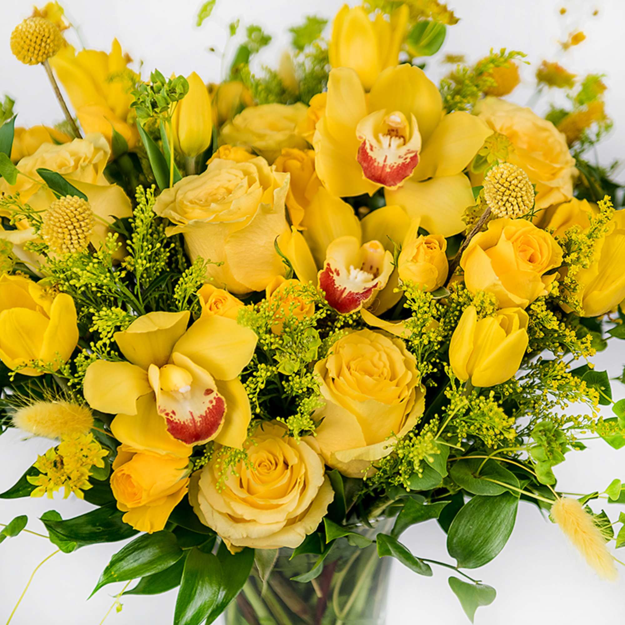 Yellow bouquet with roses, tulips, and orchids in a glass vase