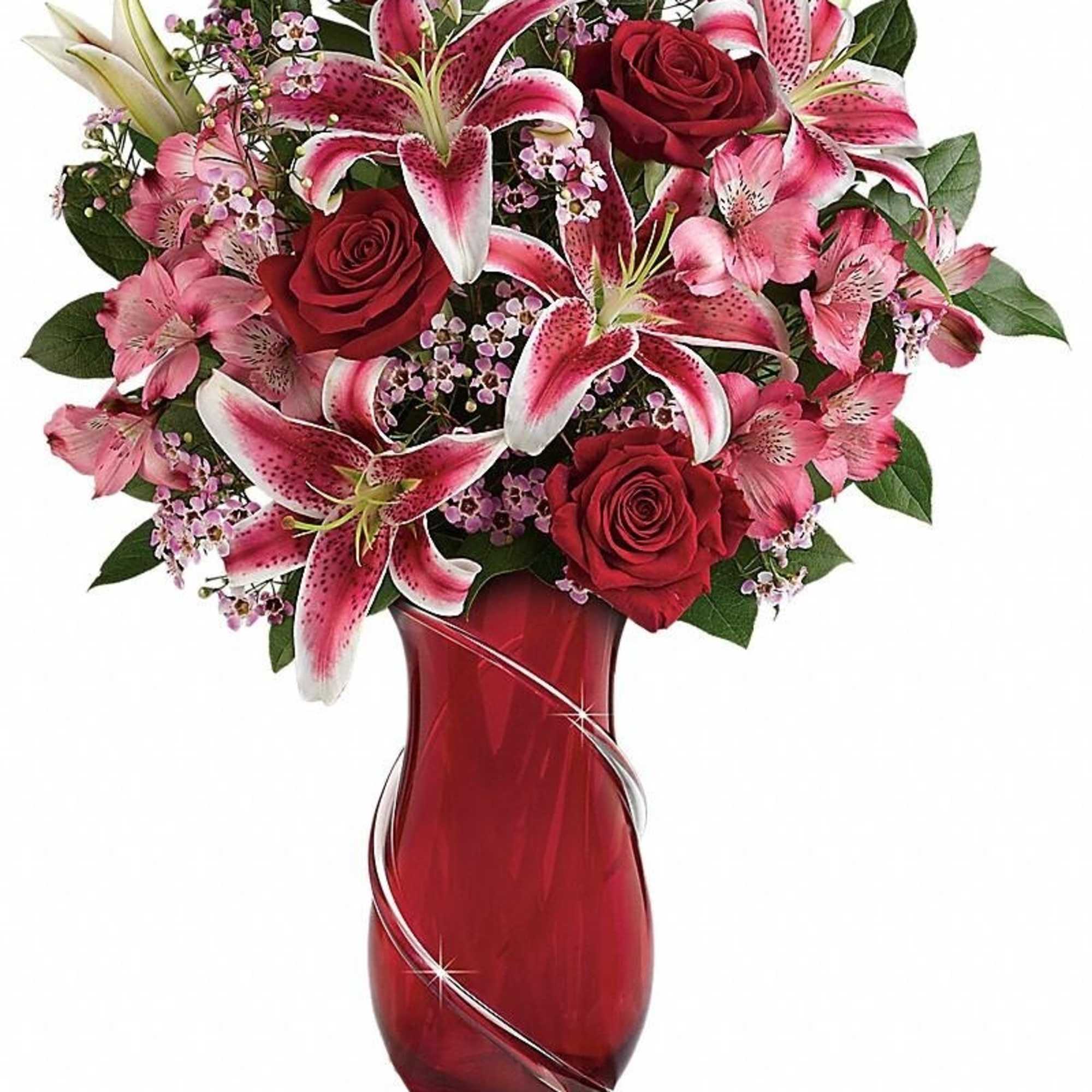 Red roses and pink lilies arranged in a red glass vase with silver swirl accents