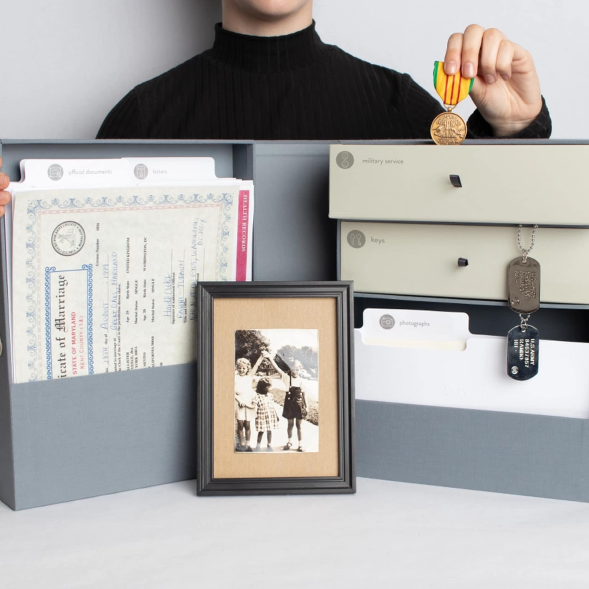 Person holding a memory box with documents, keys, and a framed photo