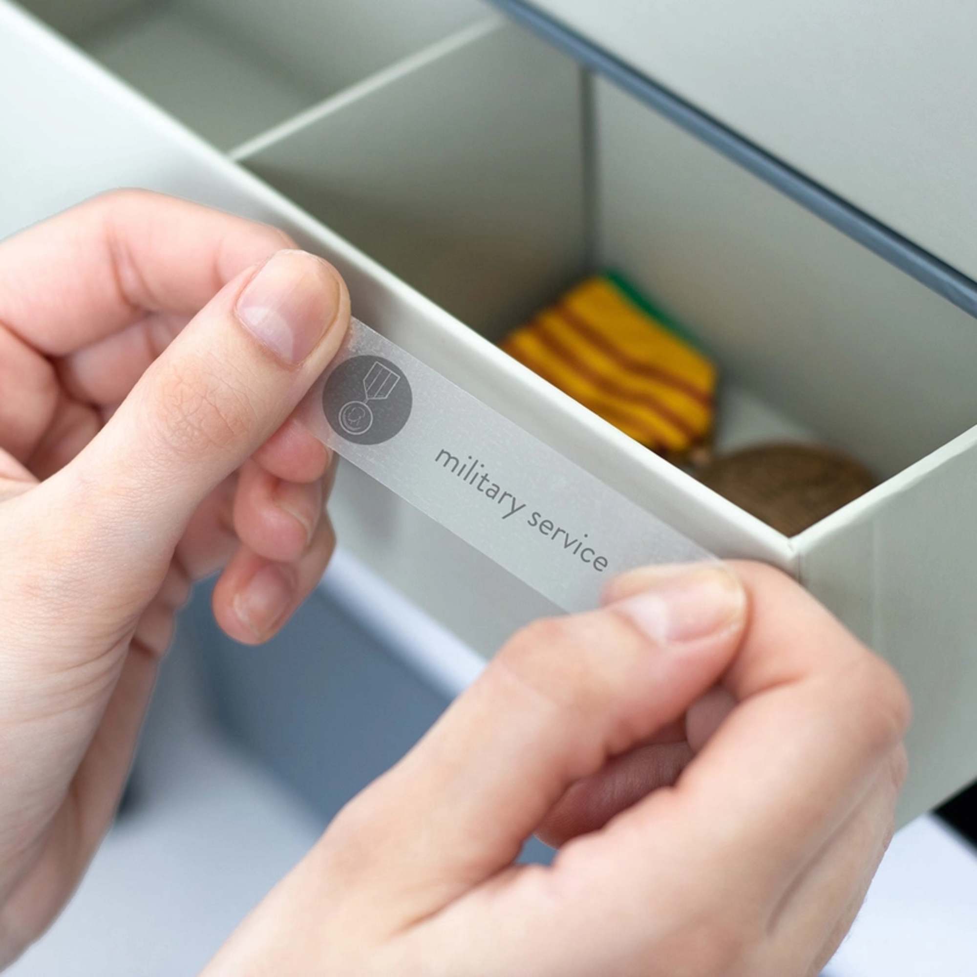 Hands placing a label in a drawer labeled military service