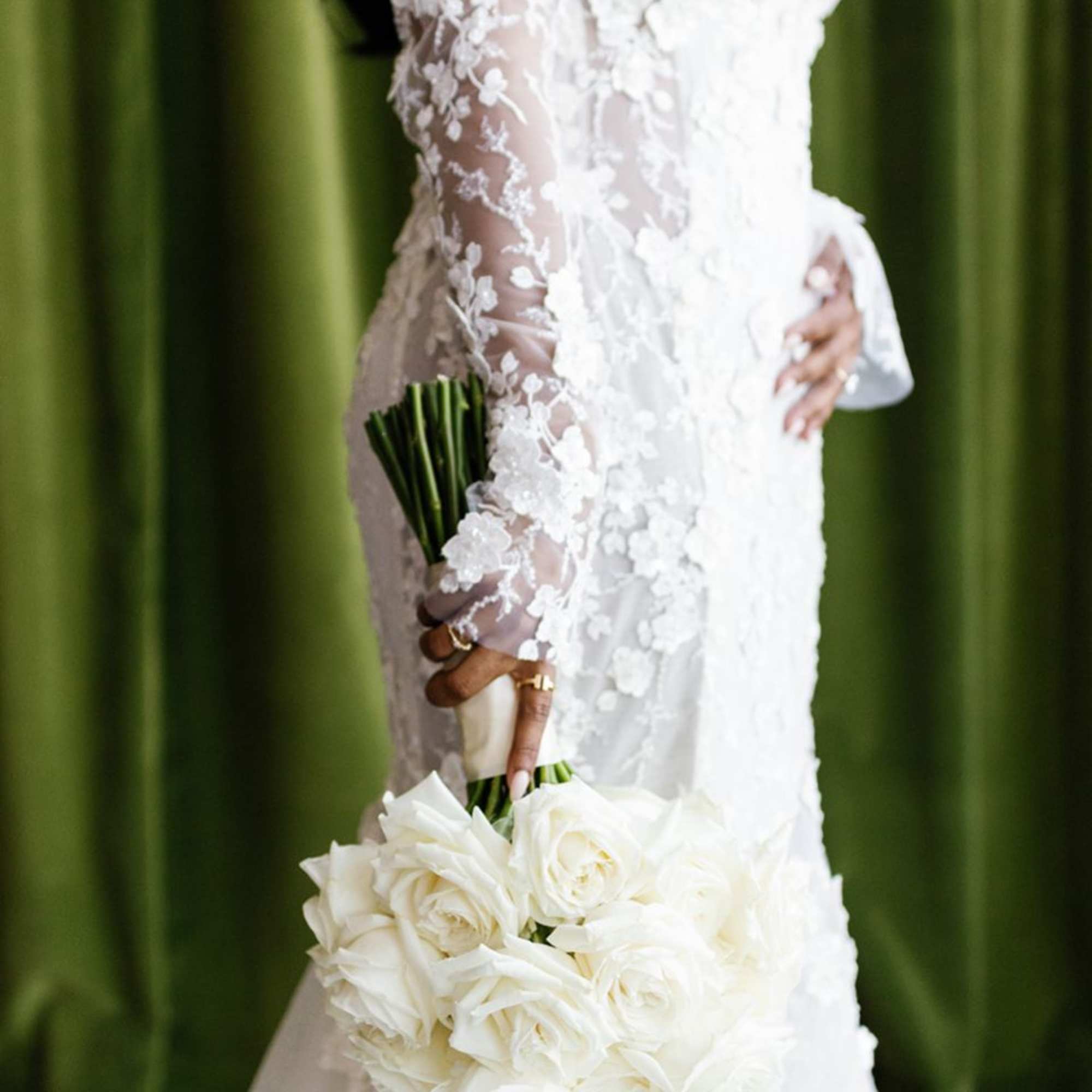 Bride in a lace dress holding a bouquet of white roses