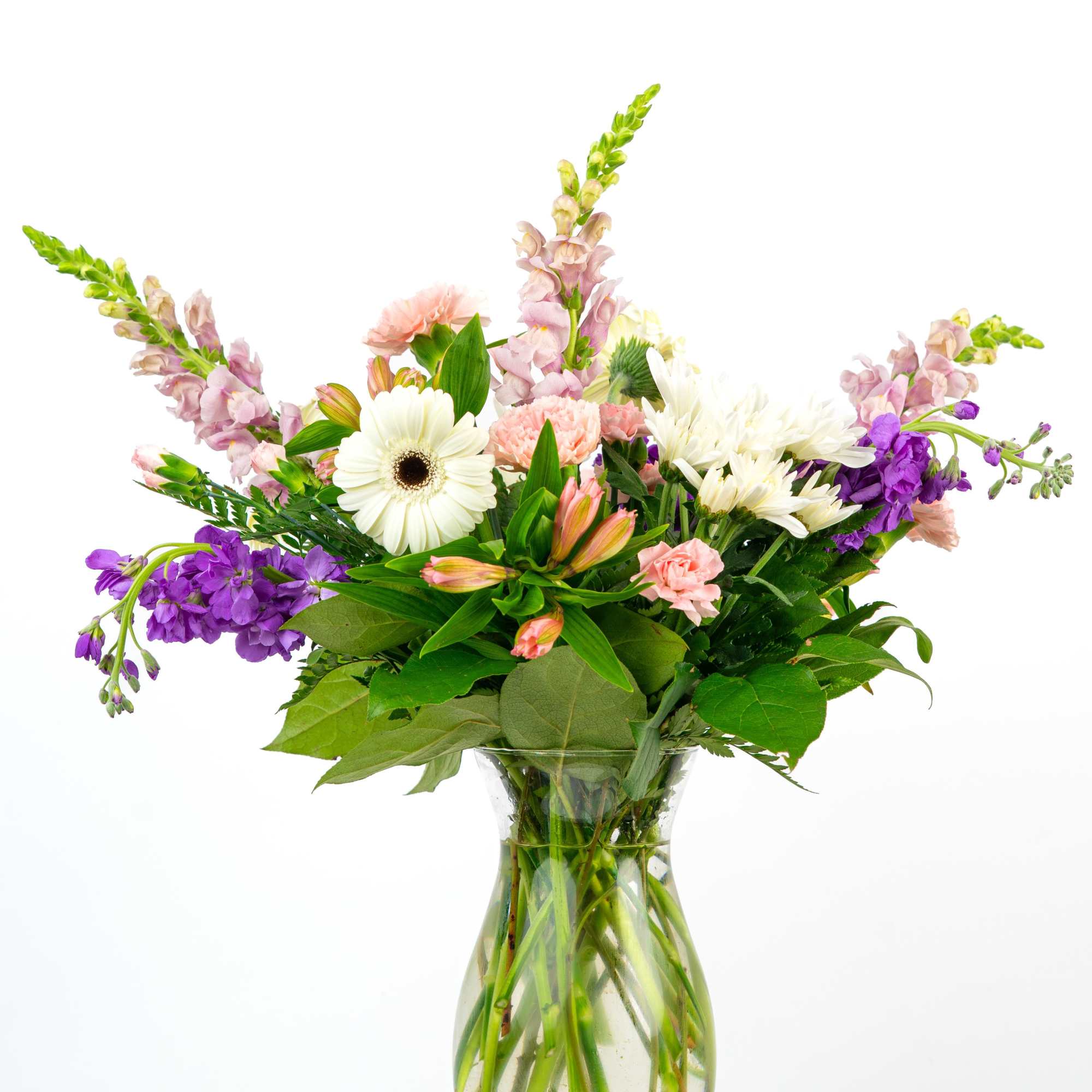 Mixed bouquet of pink, white, and purple flowers arranged in a clear glass vase