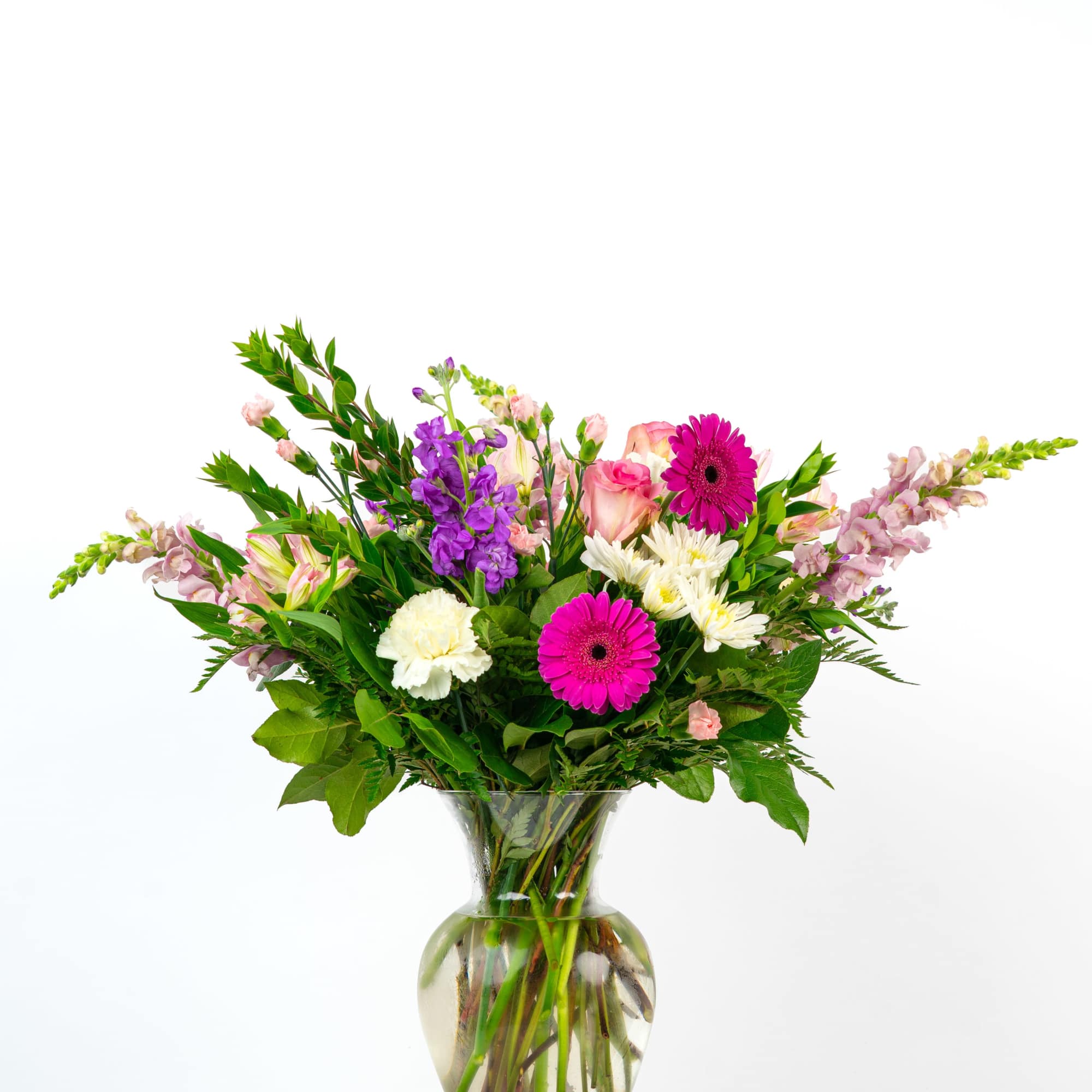 Mixed bouquet of pink, purple, and white flowers arranged in a clear glass vase.