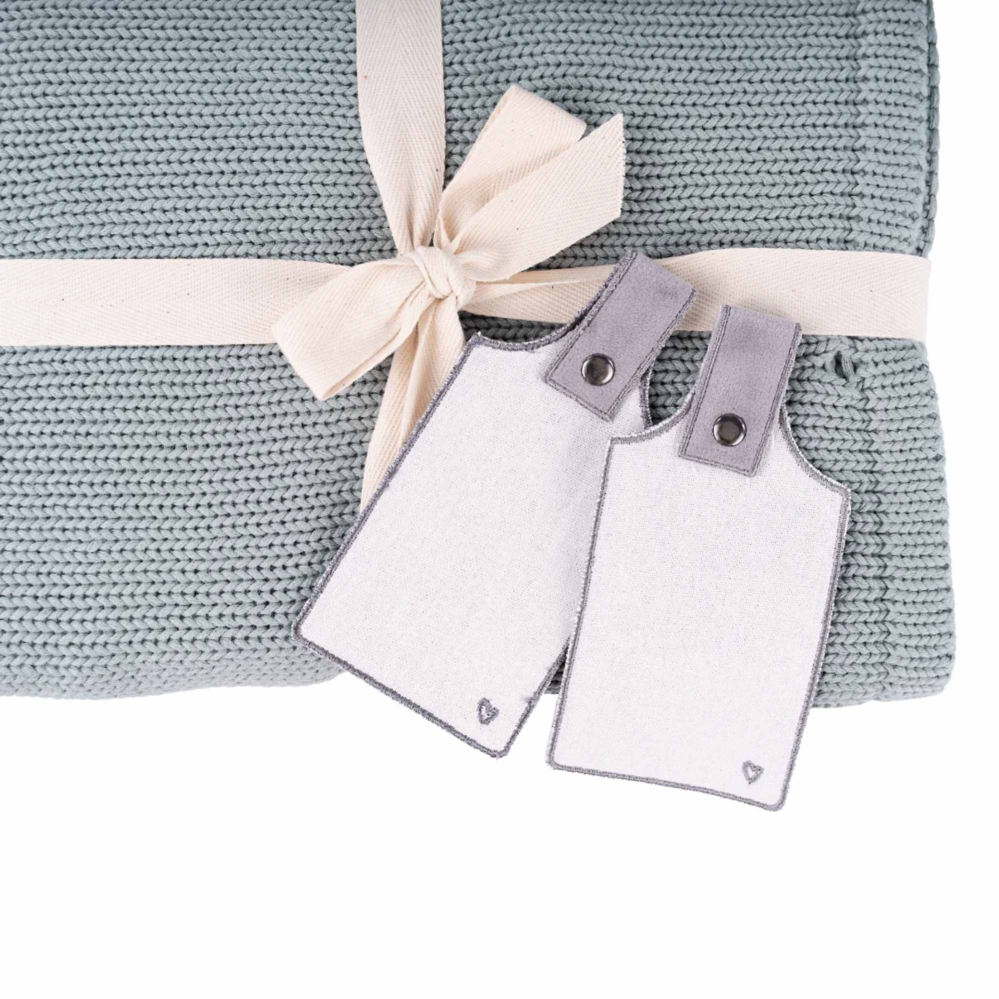 Folded knit blanket tied with ribbon and two baby tags