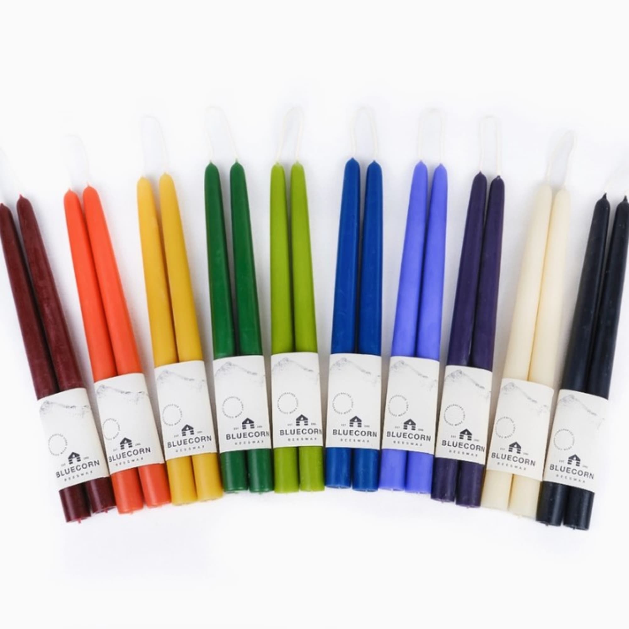 Set of multicolored taper candles arranged in a row on a white background