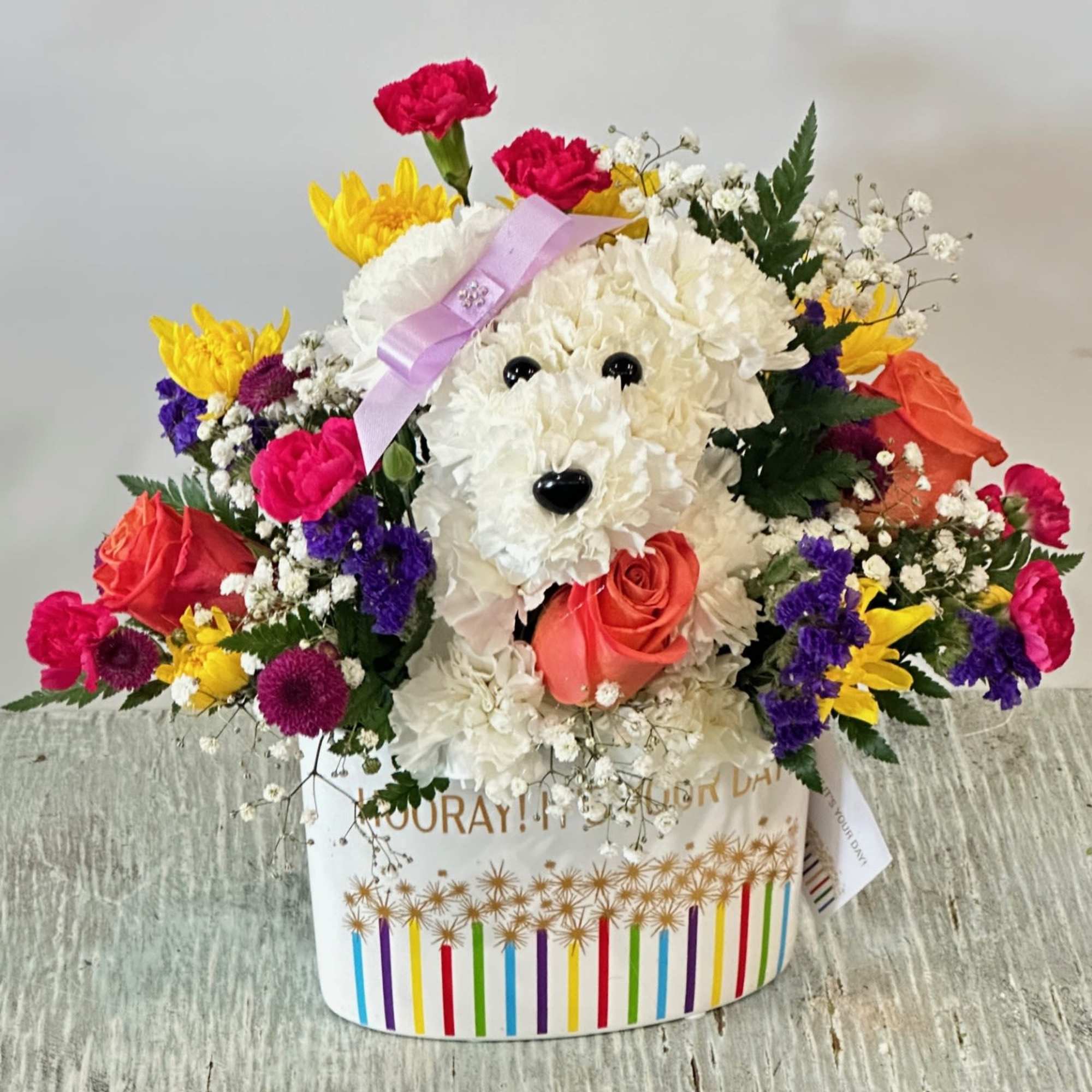 Playful dog-shaped bouquet of white carnations with colorful mixed flowers in a striped container.