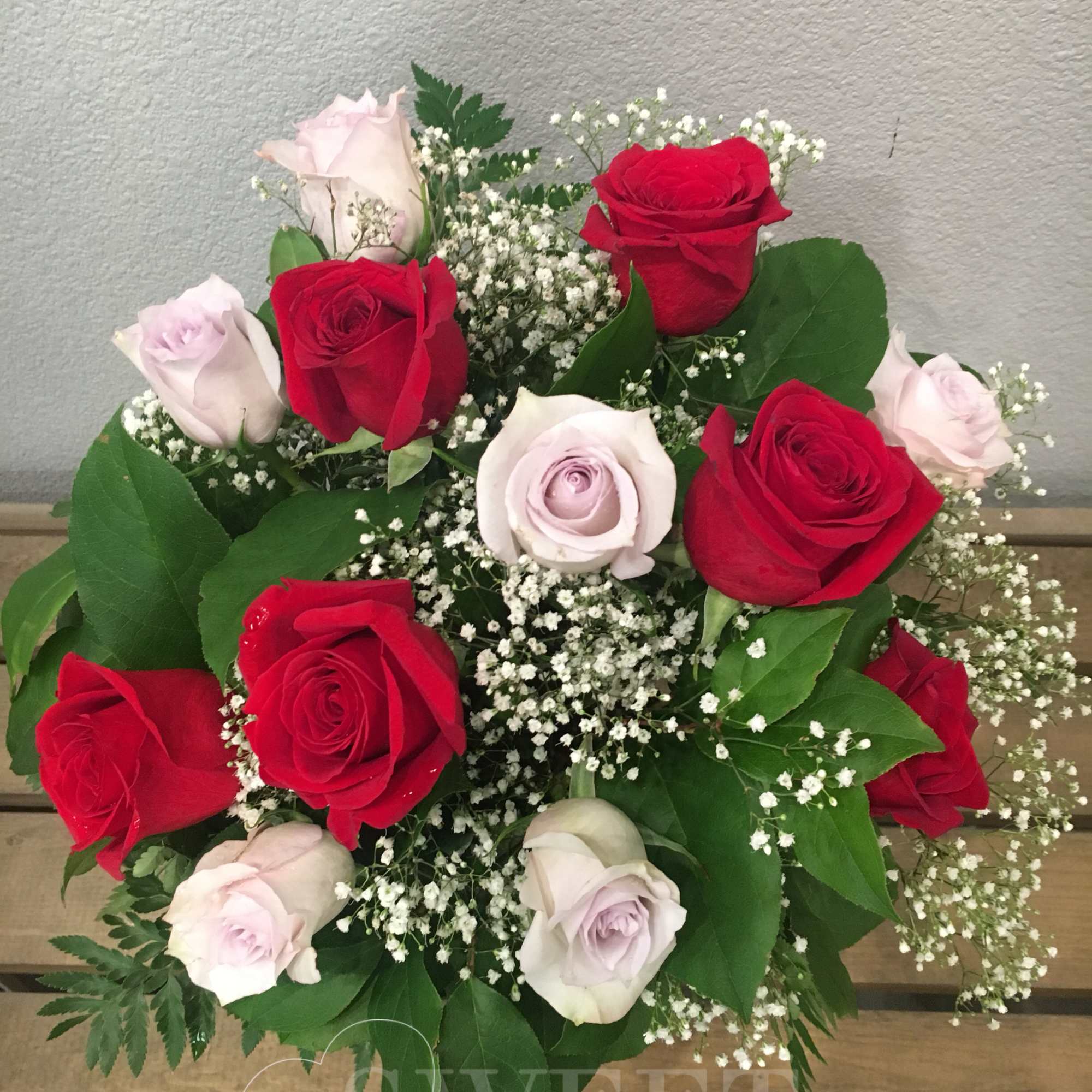 Arrangement of red and pale lavender roses with white baby's breath in a rounded bouquet