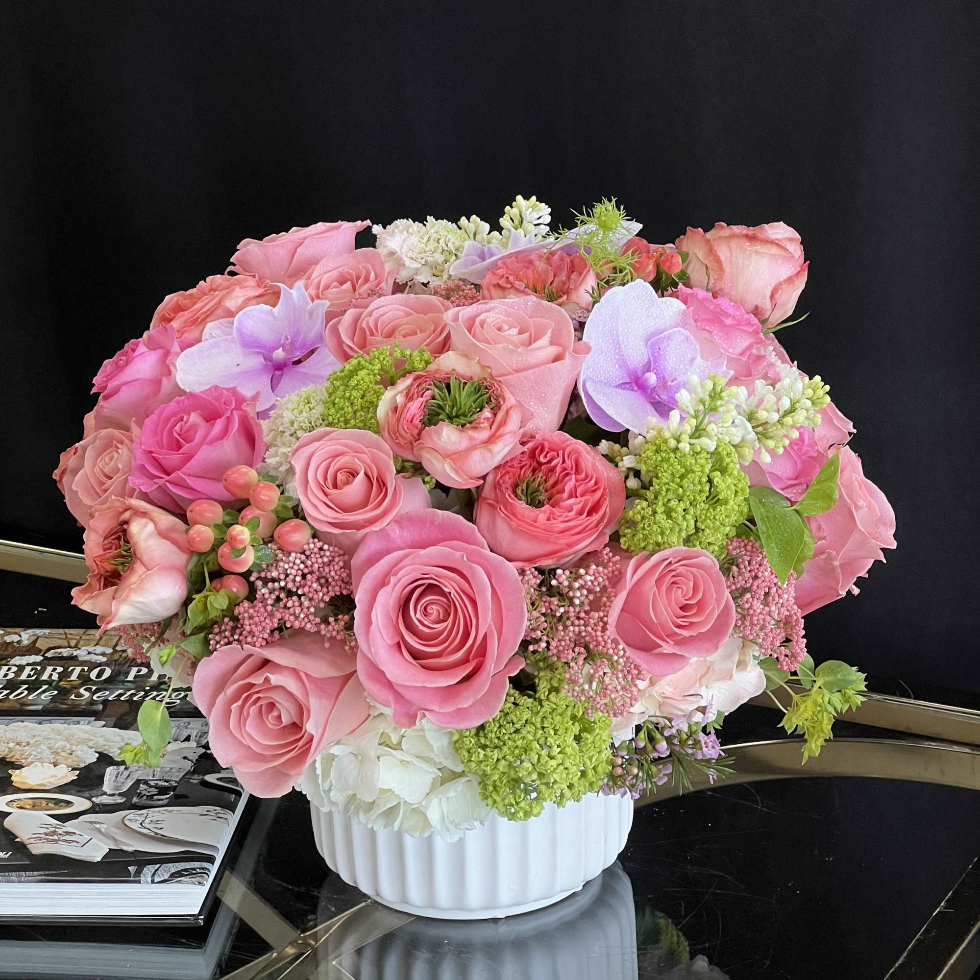 This desktop-sized floral arrangement comprises Roses, Garden Roses, Hydrangea, and Phalaenopsis Orchids