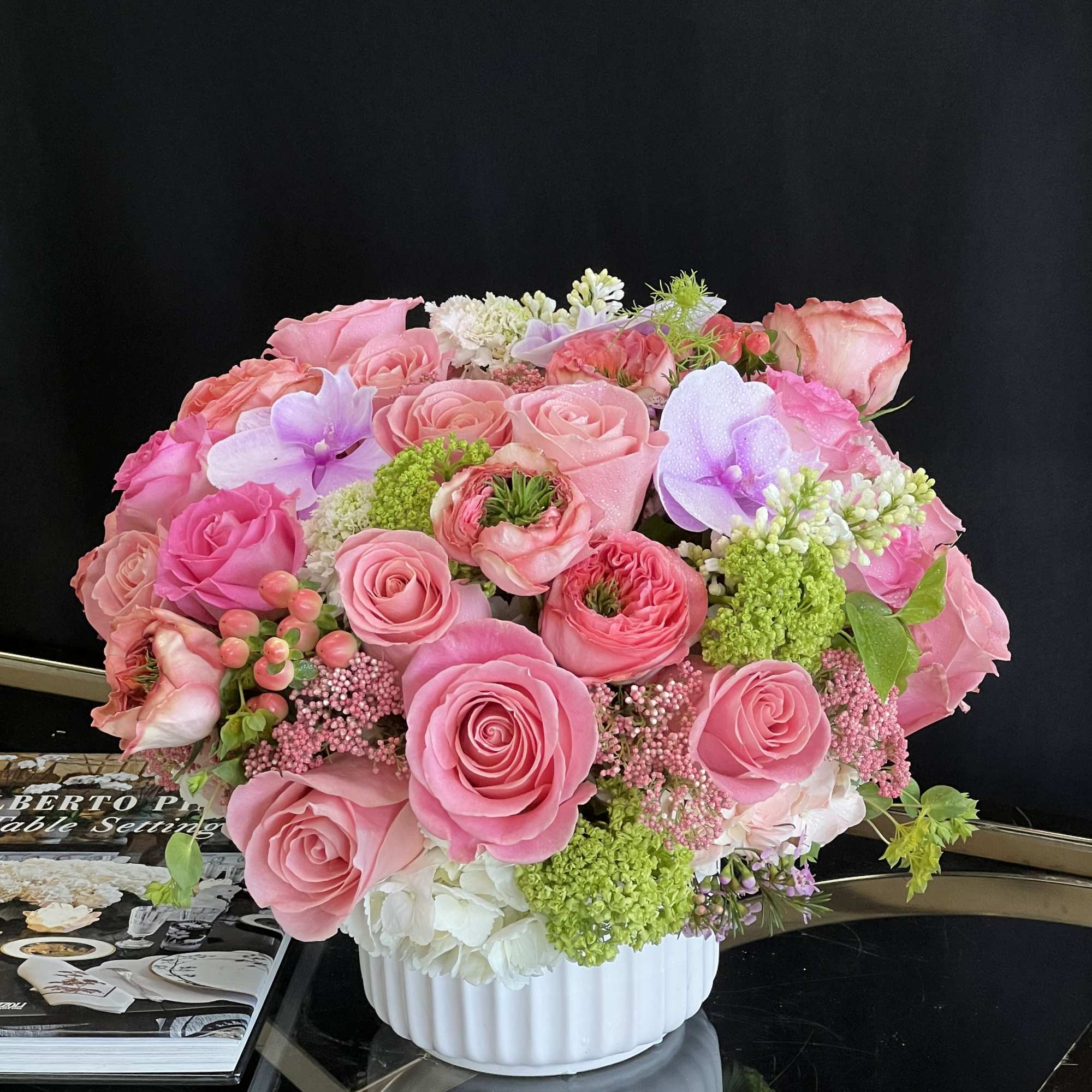 This desktop-sized floral arrangement comprises Roses, Garden Roses, Hydrangea, and Phalaenopsis Orchids