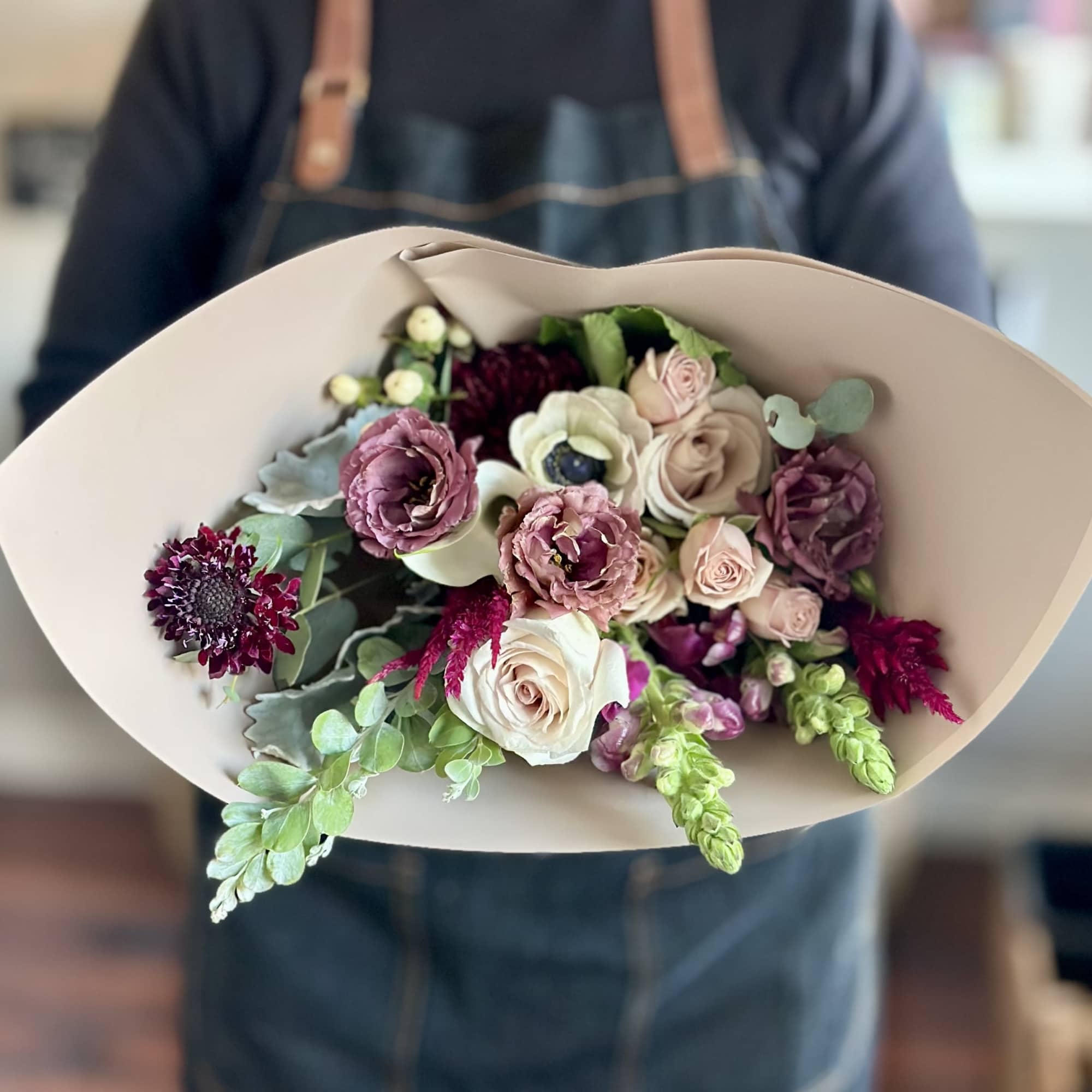 Hand-tied bouquet of pink and cream roses with purple blooms
