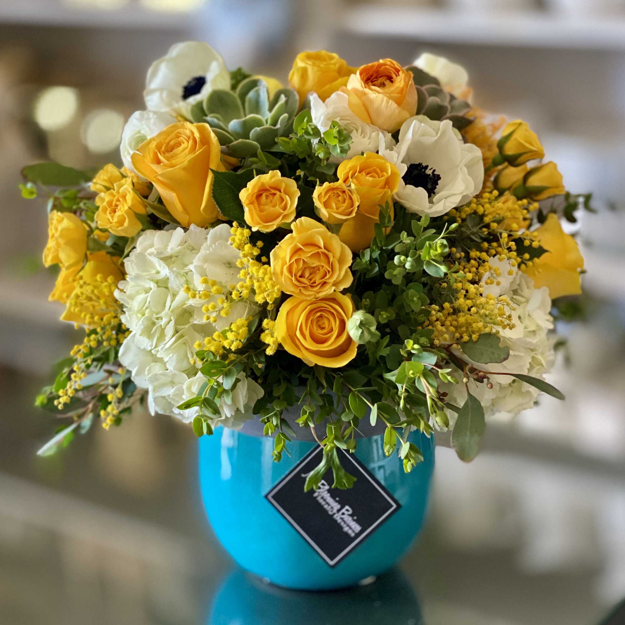 Yellow roses and white blooms in a turquoise vase