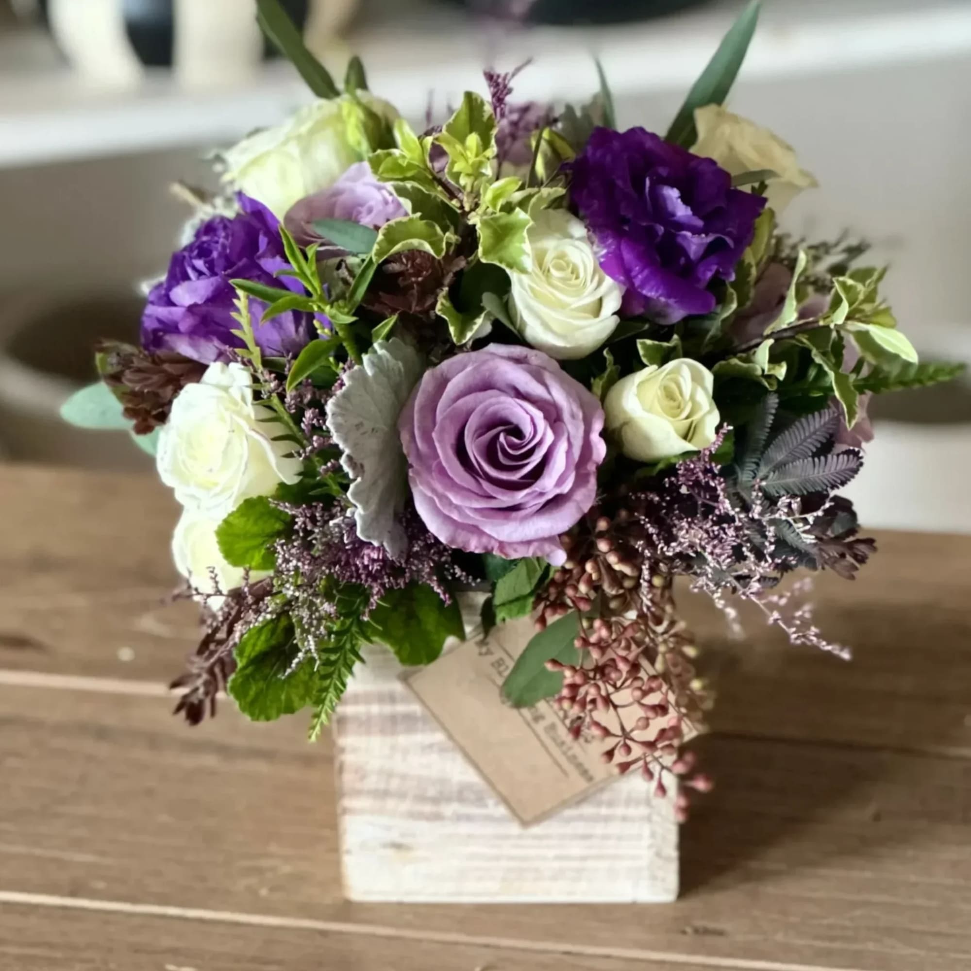 Bouquet of purple and white roses in a square vase