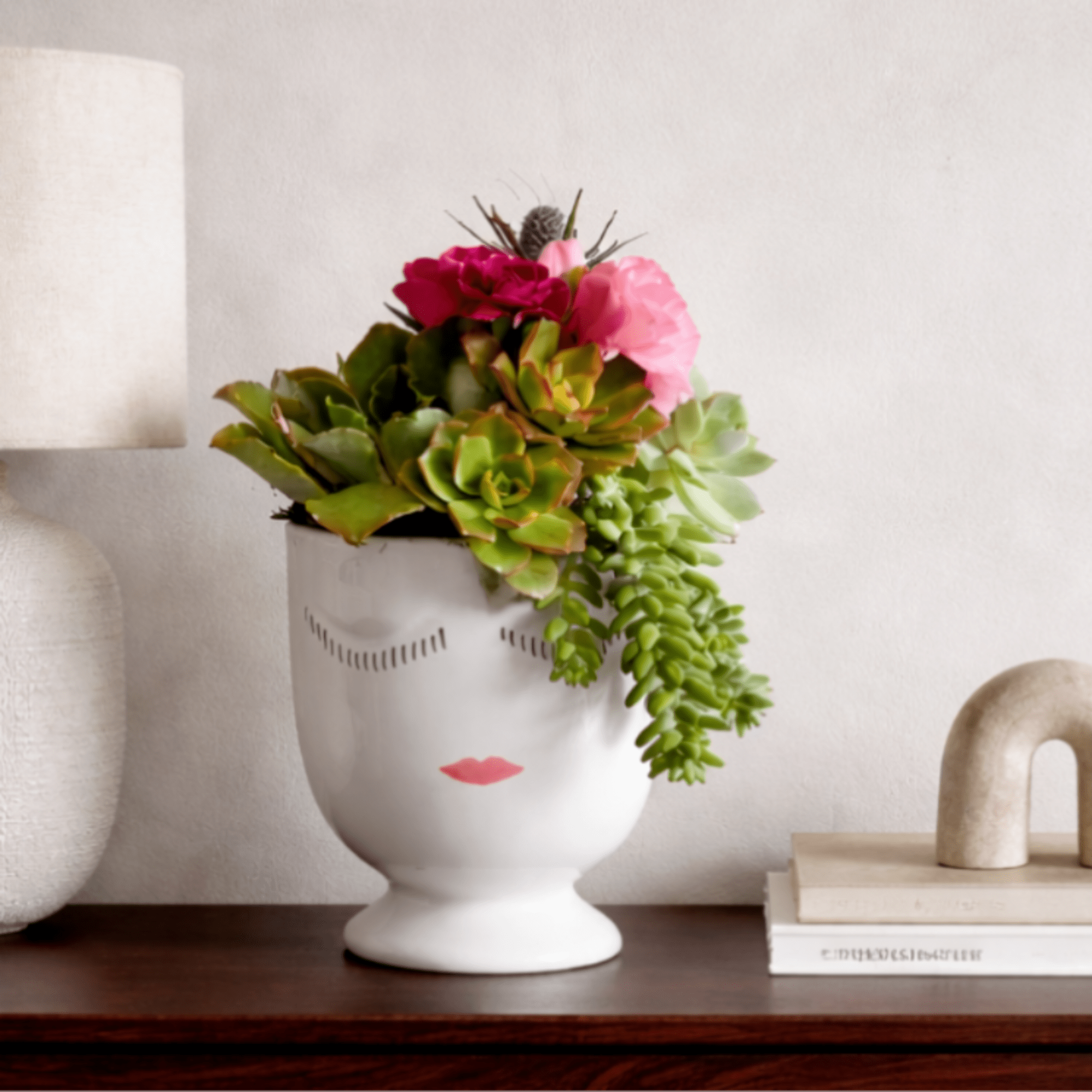 Succulent arrangement in a white face vase with pink flowers