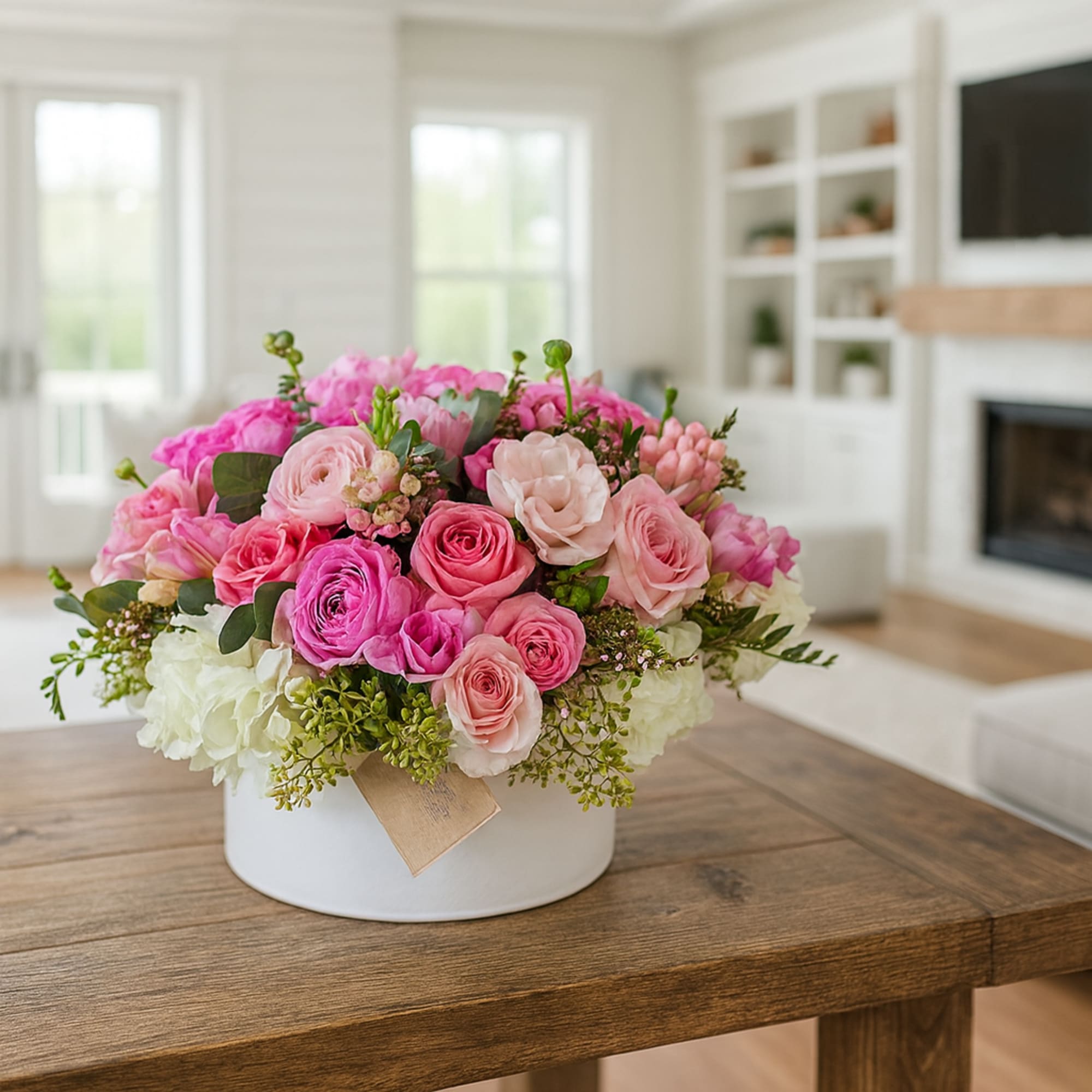 Pink and white rose arrangement in a white round box