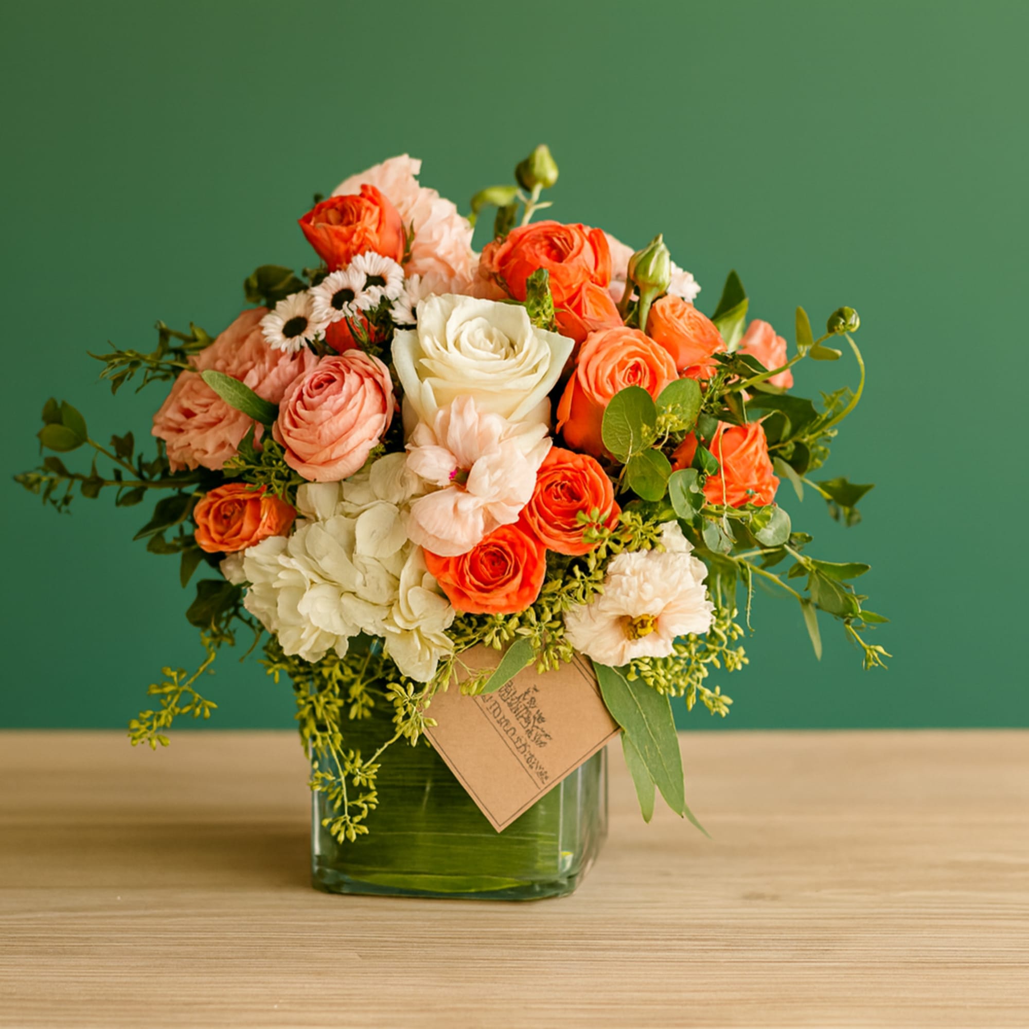 Bouquet of orange, peach, and white roses in a glass vase