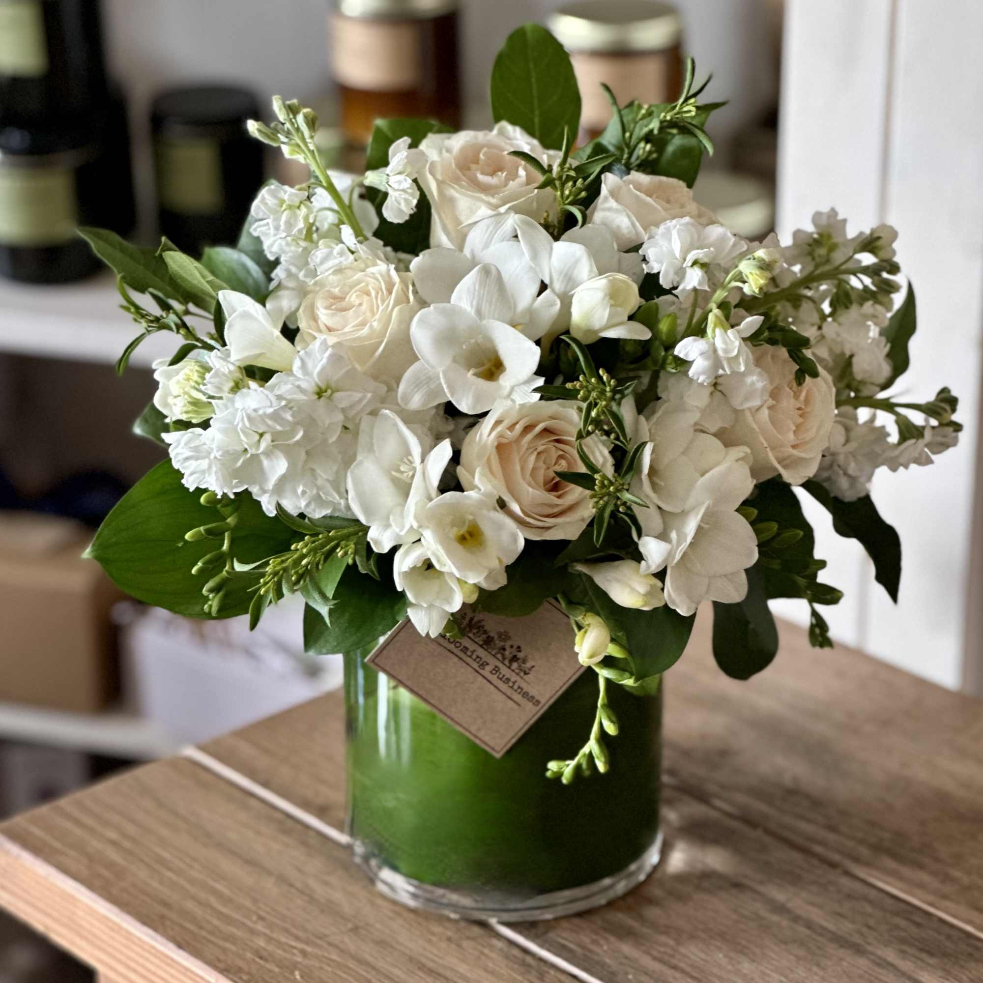 White and blush bouquet in a green glass vase