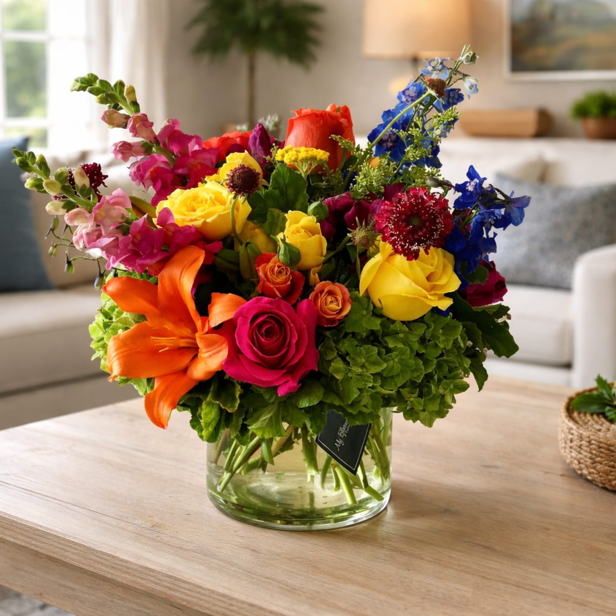 Colorful mixed bouquet in a clear glass vase on a coffee table