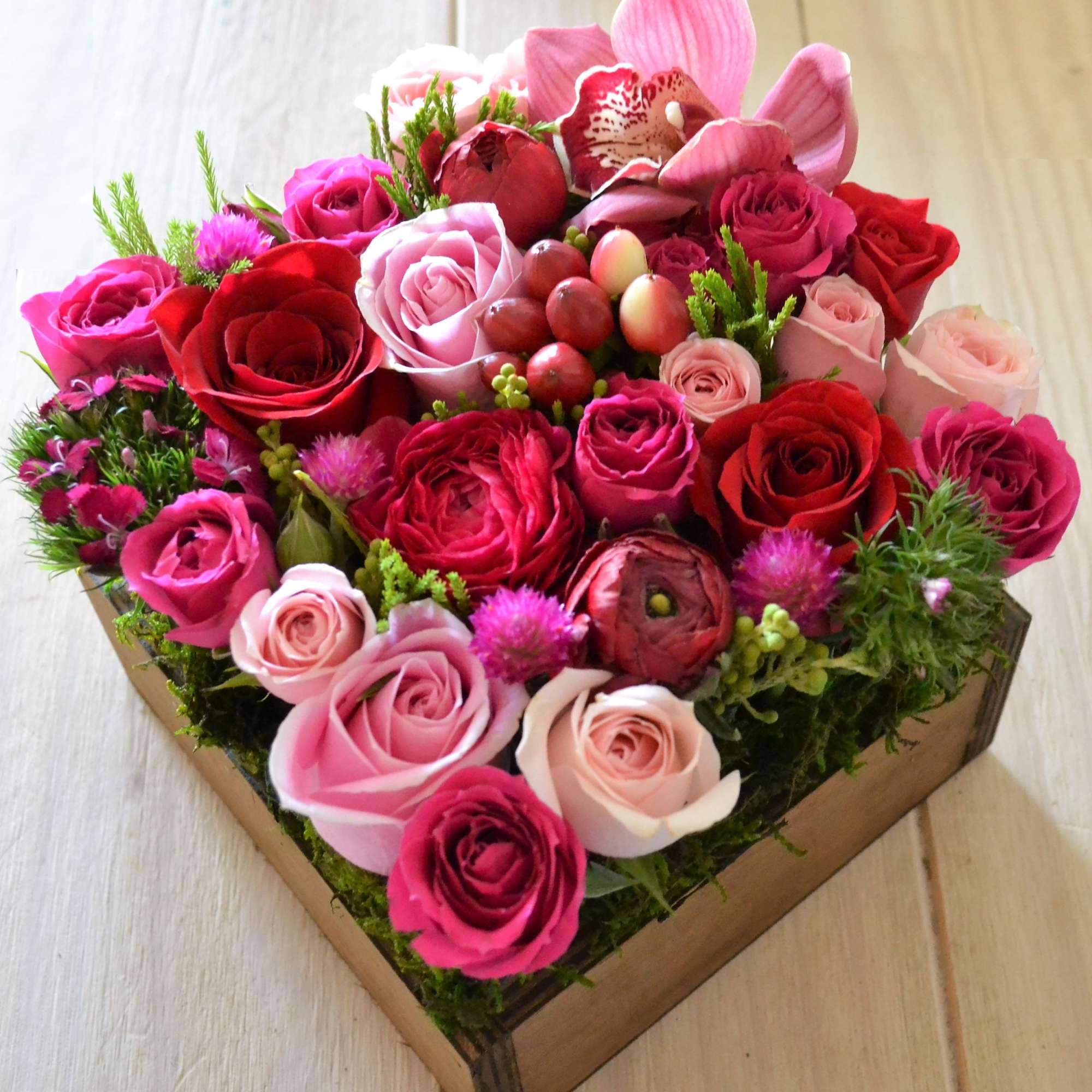 Heart-shaped box filled with pink and red roses and orchids