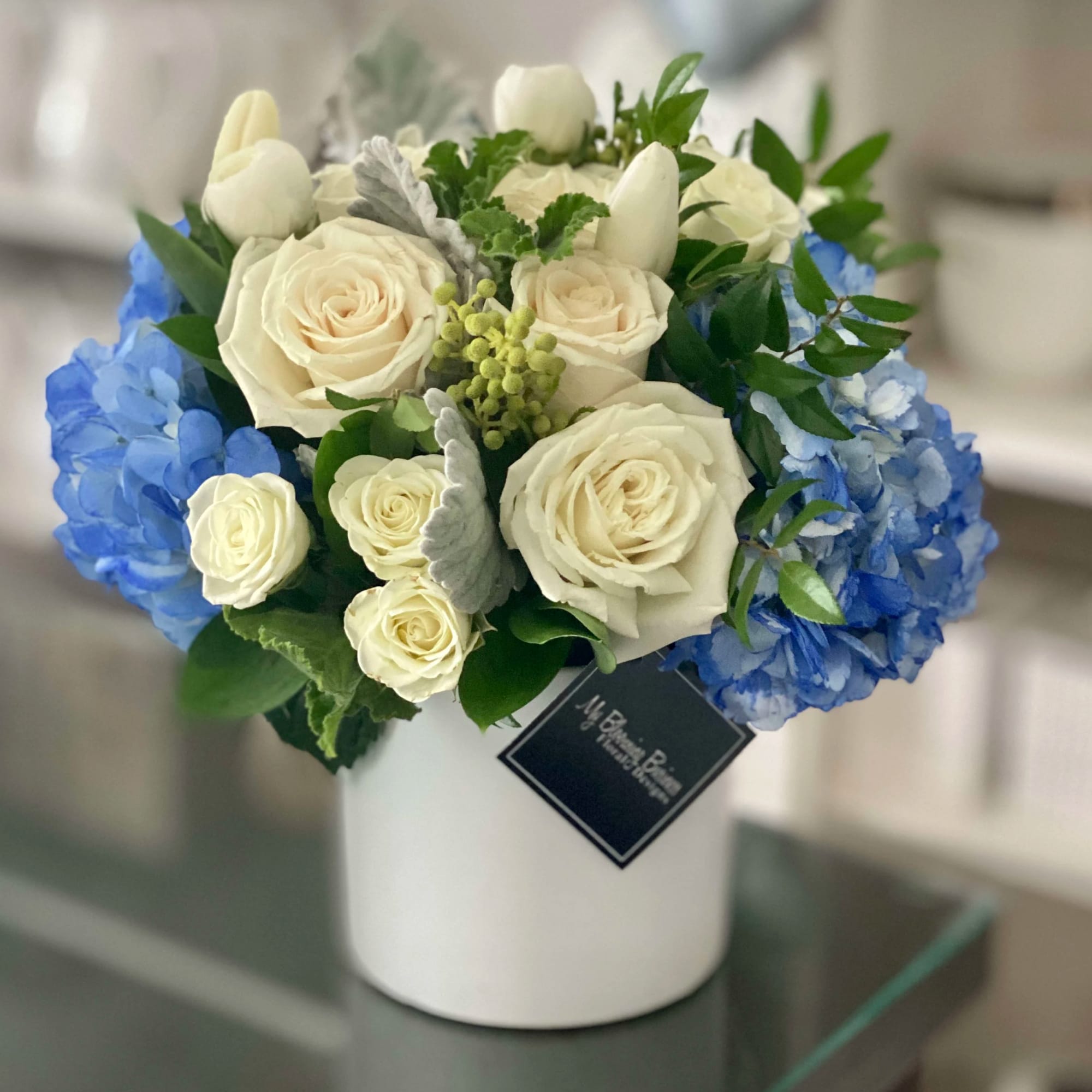 White roses and blue hydrangeas in a white vase