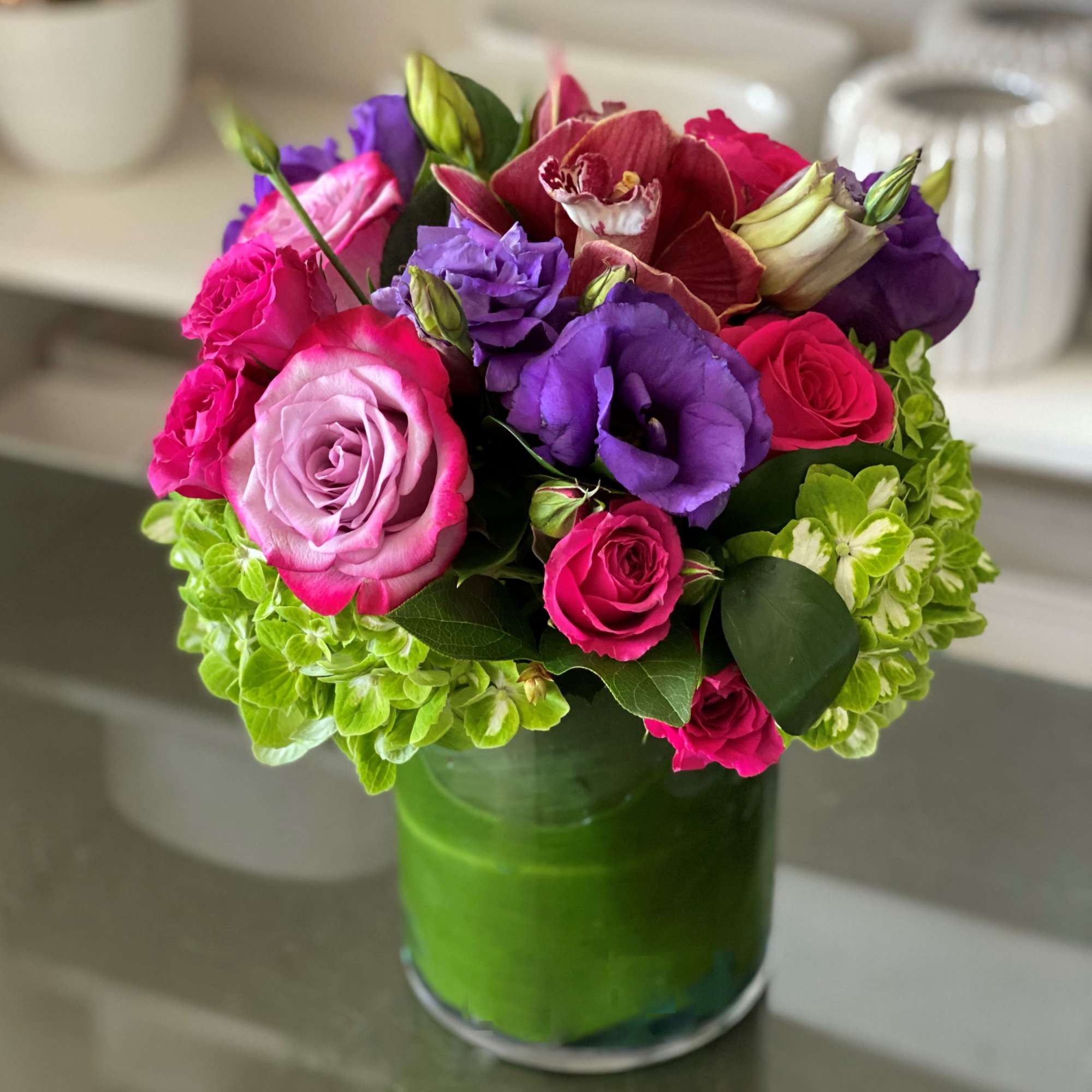 Pink and purple bouquet in a green glass vase