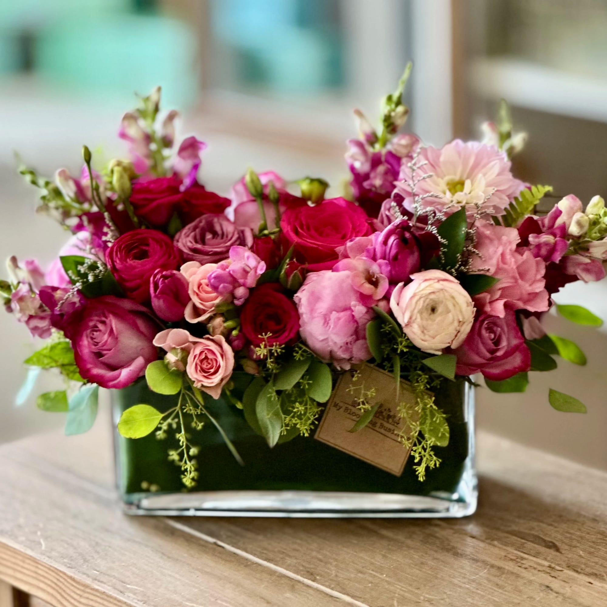 Pink and magenta floral arrangement in a rectangular glass vase