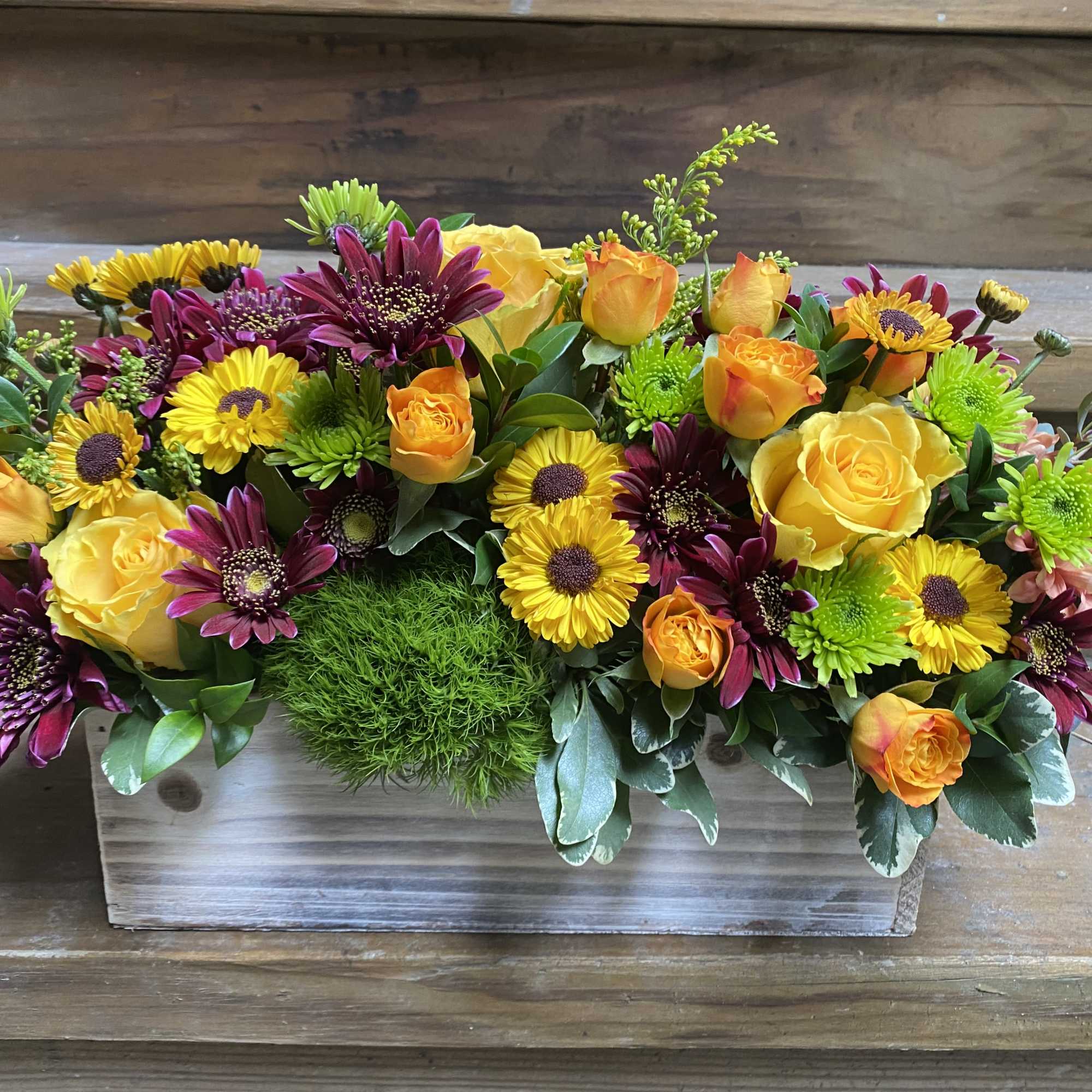 Mixed yellow and purple flowers arranged in a wooden box