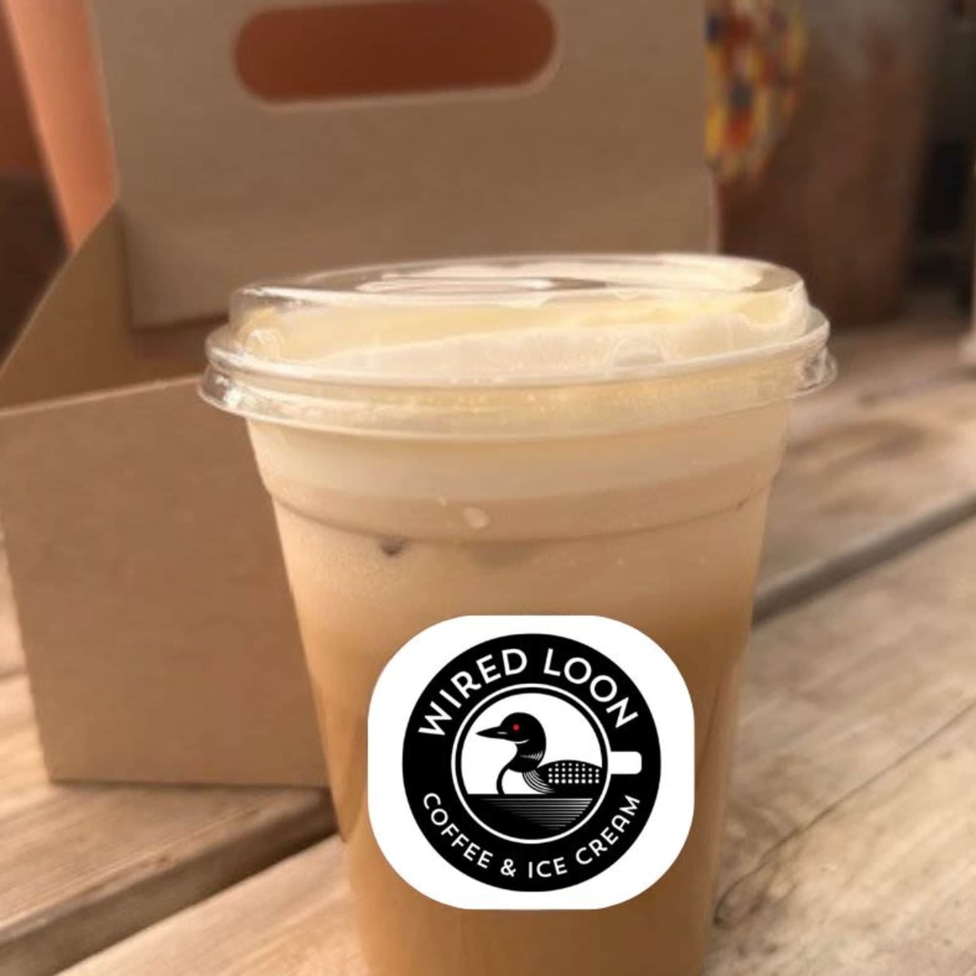 Iced coffee in a clear plastic cup with a lid and logo sticker