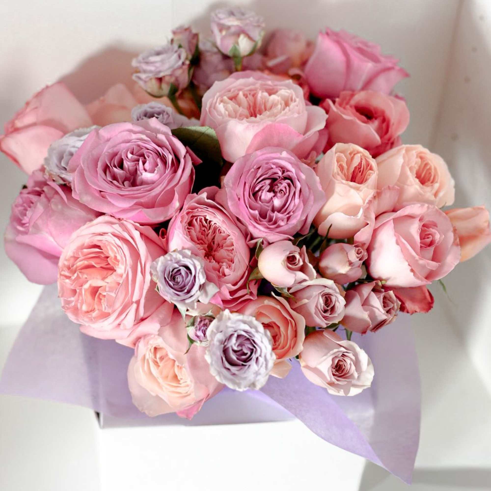 Bouquet of pink and lavender roses wrapped in pale purple paper