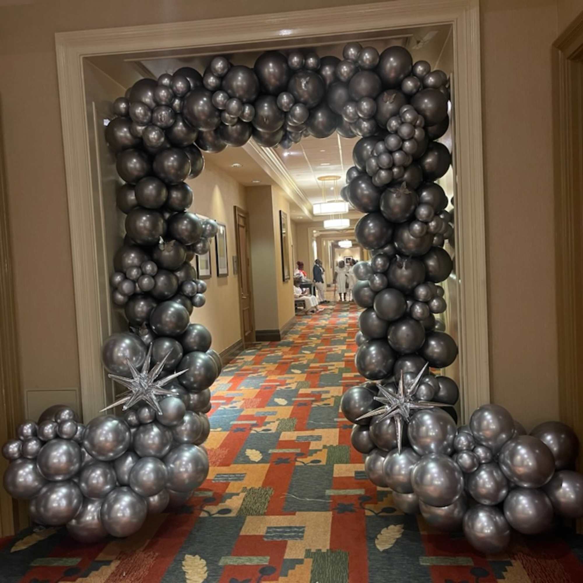 Metallic silver and black balloon arch framing a hallway doorway