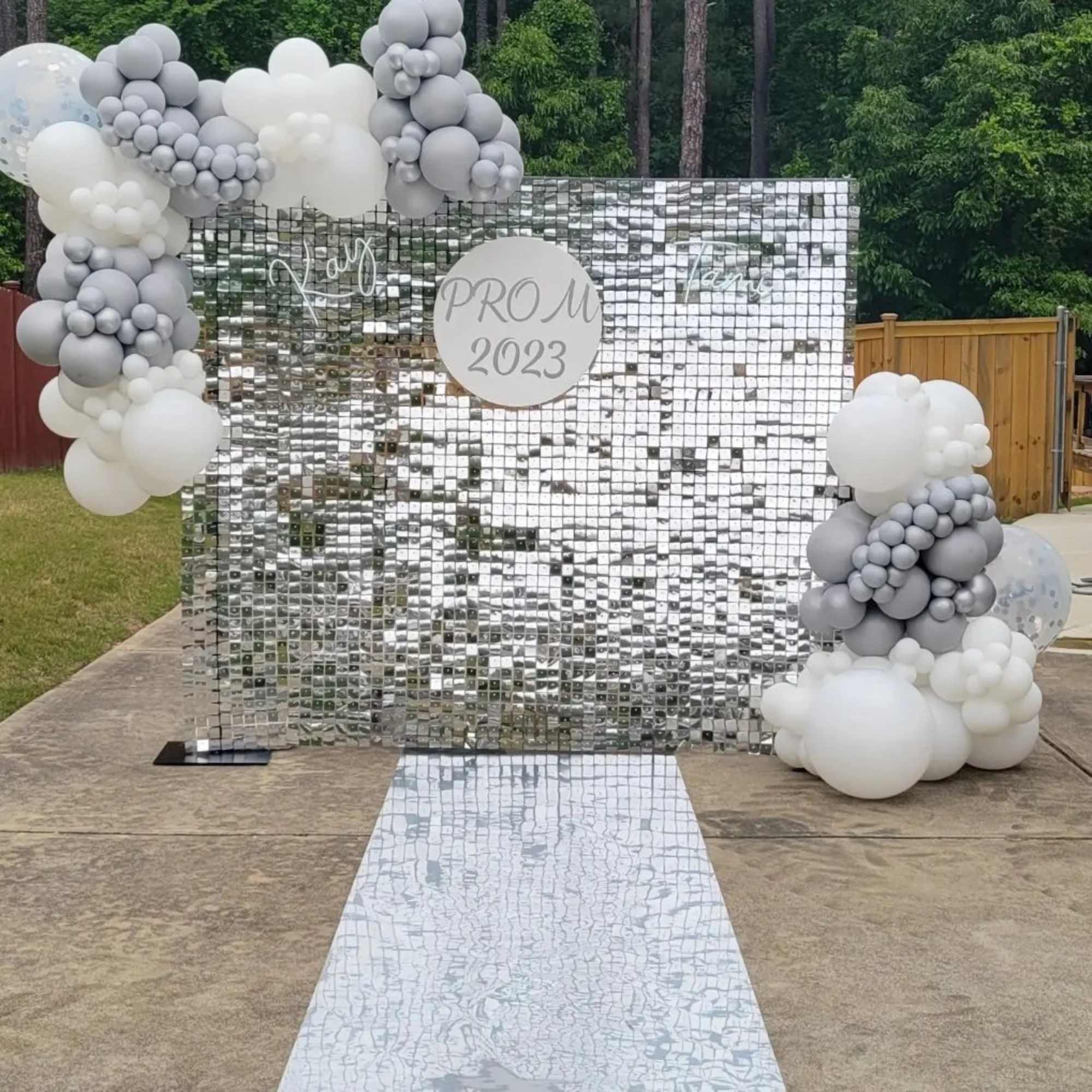 Silver sequin backdrop with gray and white balloon clusters and a mirrored aisle runner
