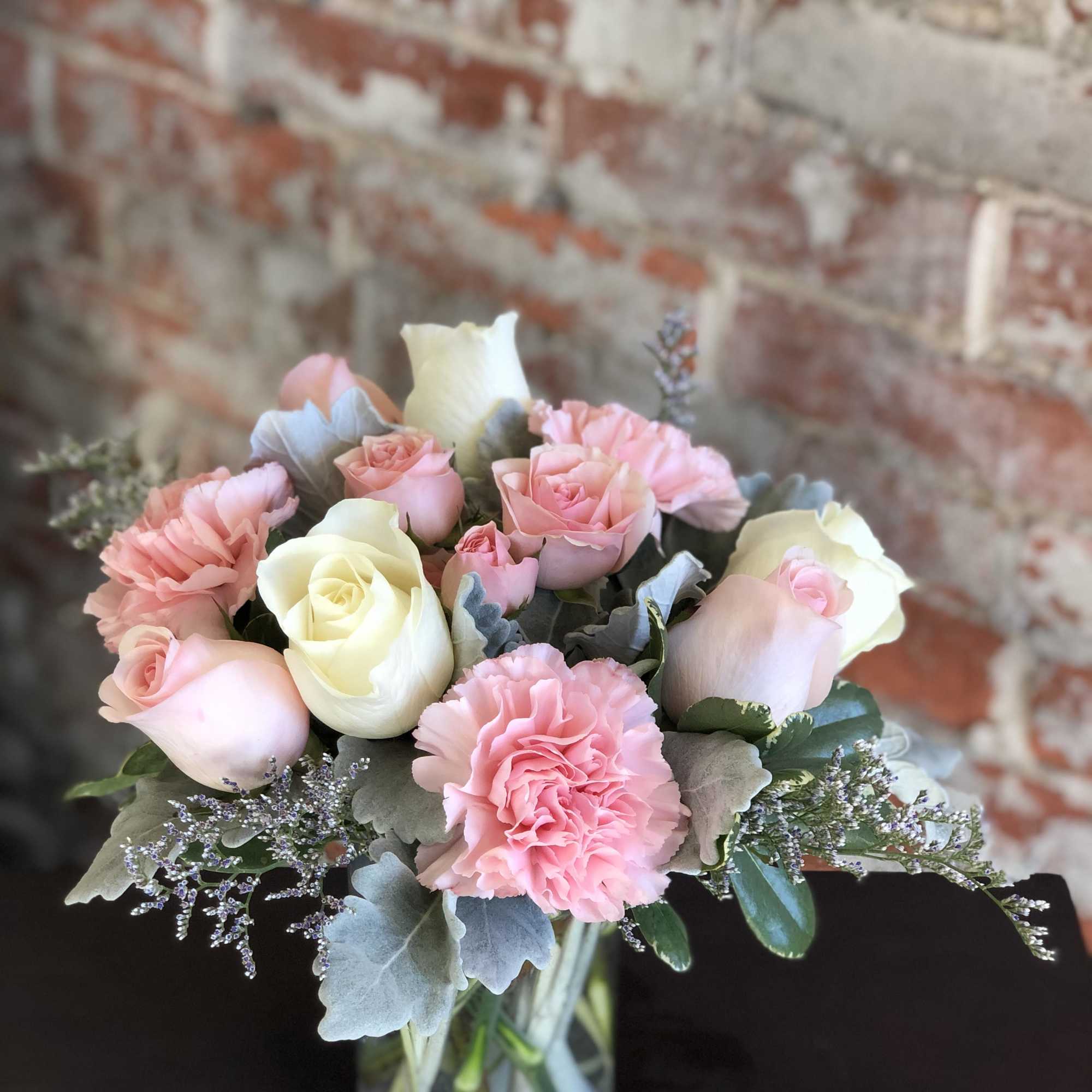 Pink and white roses with carnations in a glass vase