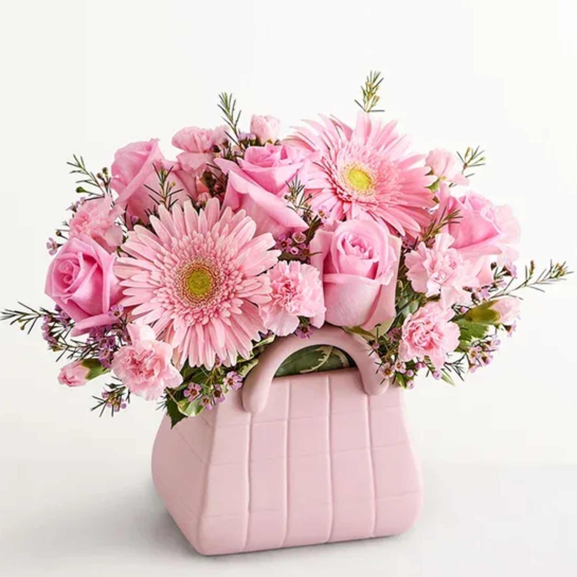 Arrangement of pink roses, Gerbera daisies, mini carnations, and waxflowers accented with
