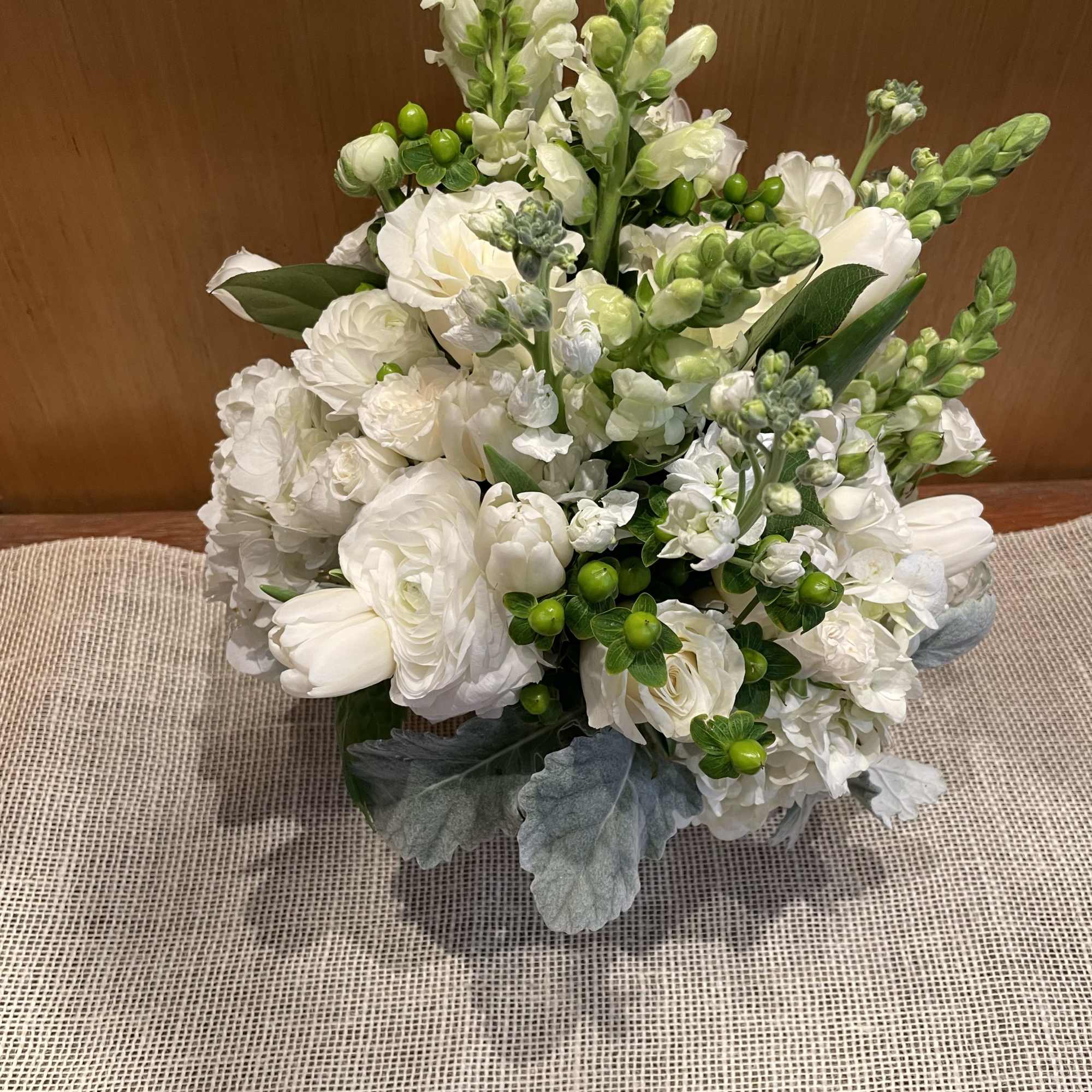 White floral arrangement with green accents in a low container